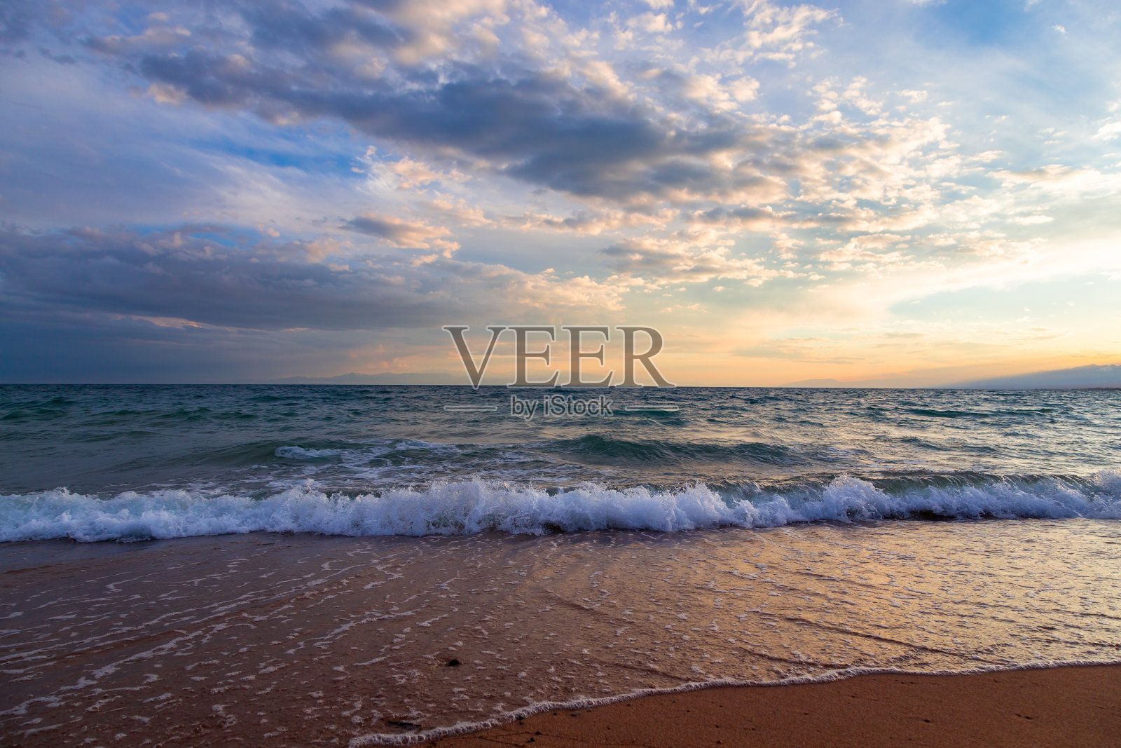 湖边美丽的日落。明亮的云倒映在水面上。吉尔吉斯斯坦。照片摄影图片