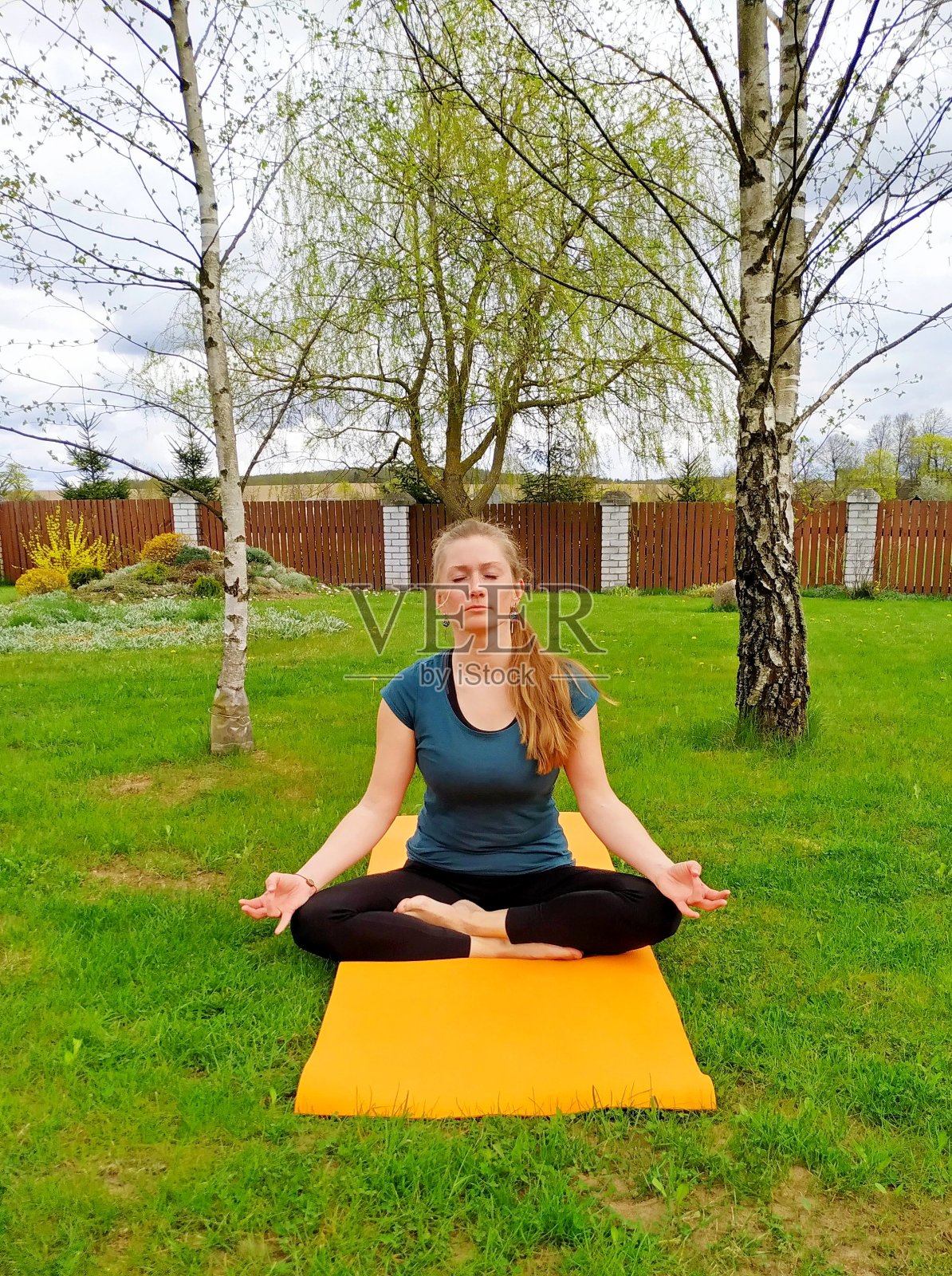 一名年轻女子在后院的树林里练习瑜伽照片摄影图片