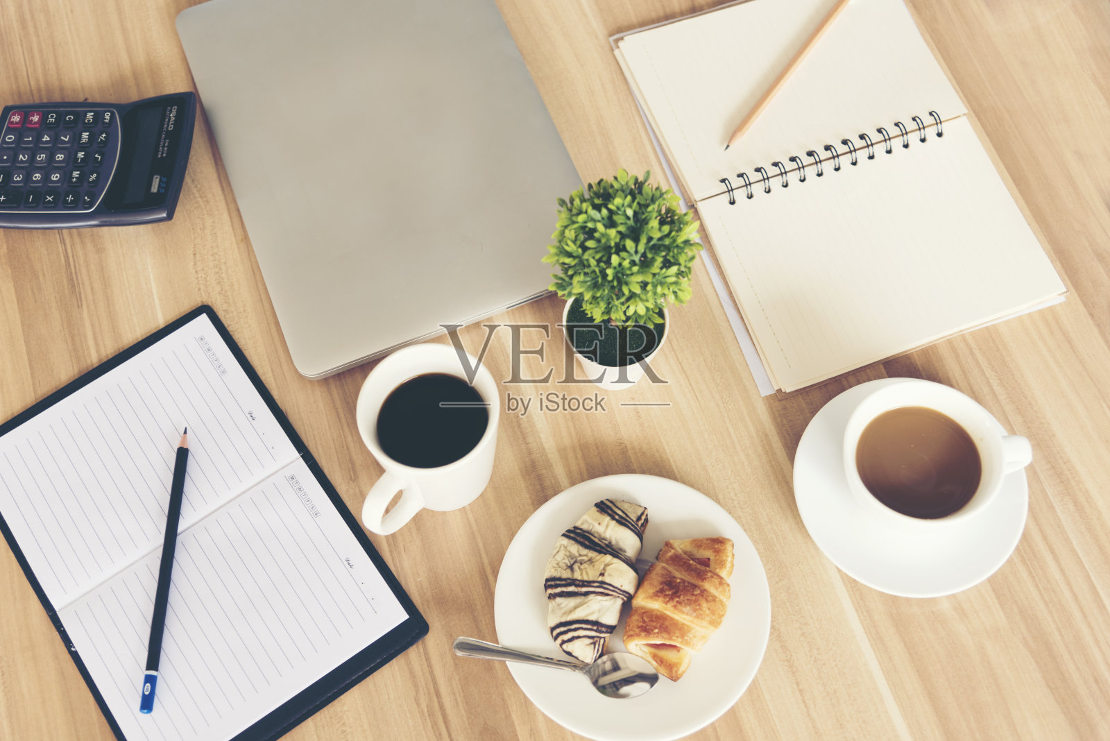 俯视图的团队会议显示杯咖啡，笔记本电脑，笔记本电脑在木桌上。照片摄影图片