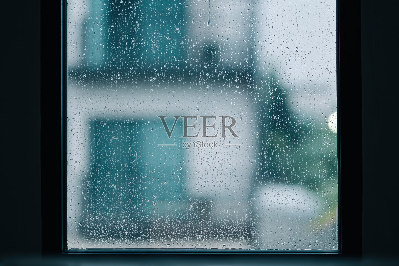 下雨天，窗外的玻璃在模糊的背景下随着水滴流下照片摄影图片