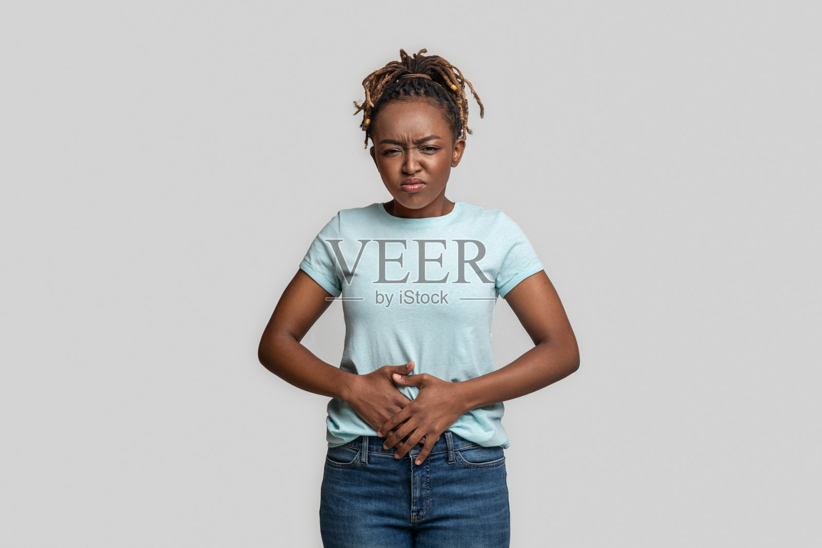 悲伤的黑人女孩摸着她的肚子，灰色的背景照片摄影图片