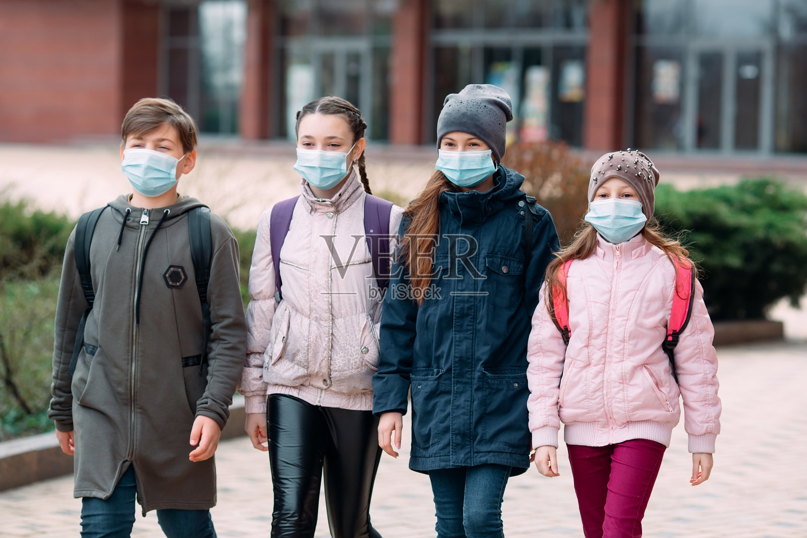 学生们戴着医用口罩离开学校。照片摄影图片