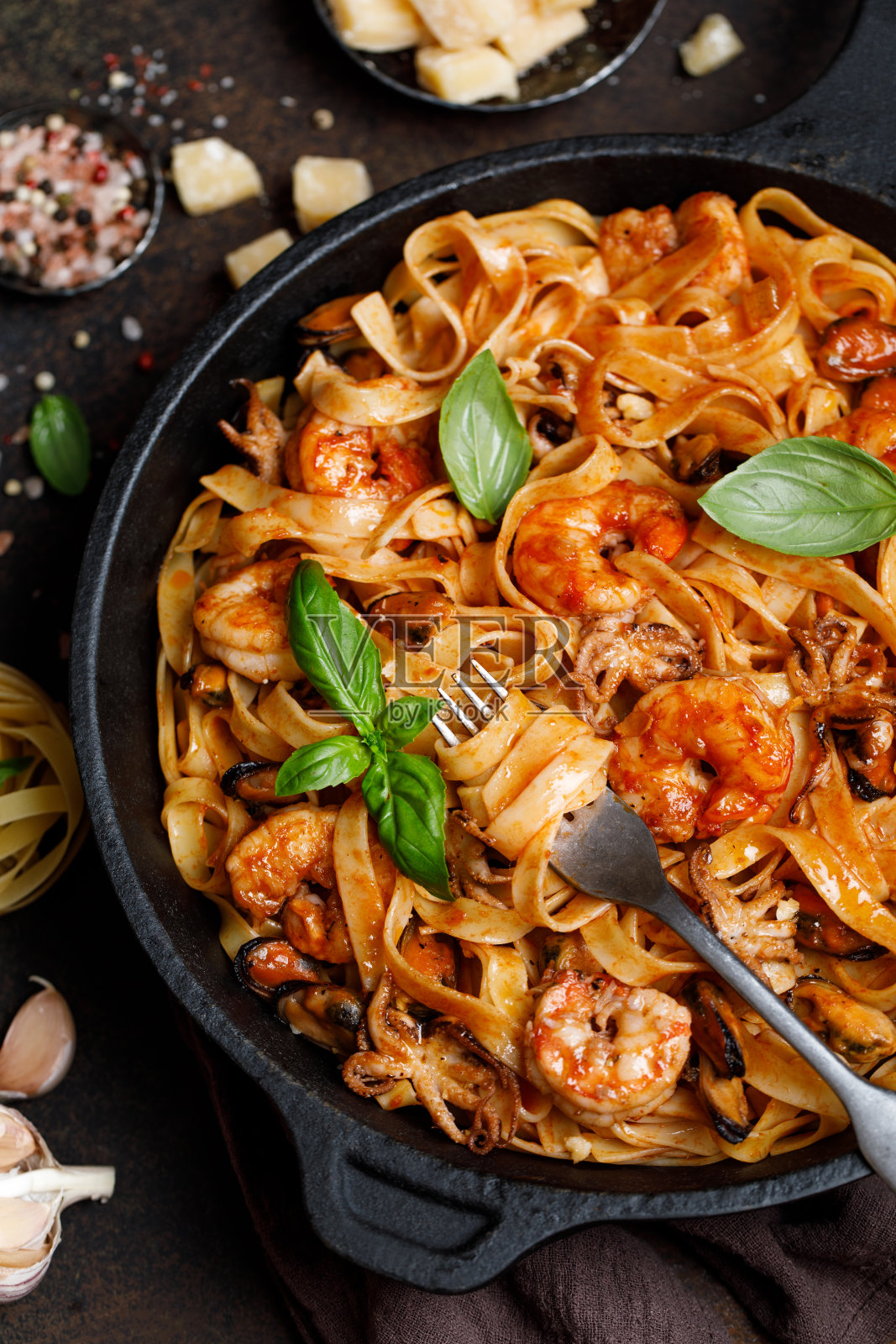 加海鲜的意大利宽面条。海鲜意面，贻贝，虾，章鱼和罗勒在铸铁平底锅照片摄影图片