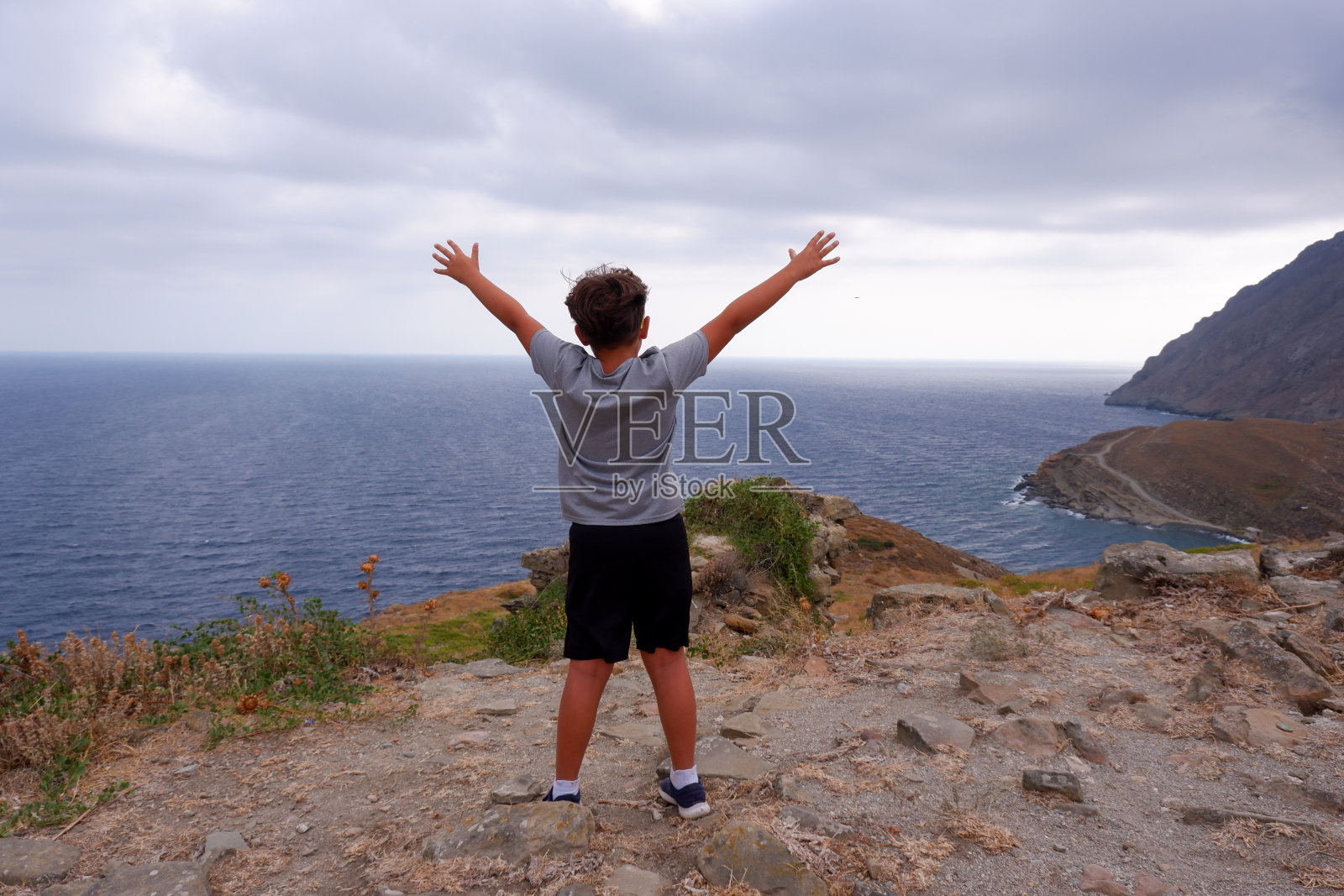 快乐的男孩和他的手在山上。照片摄影图片