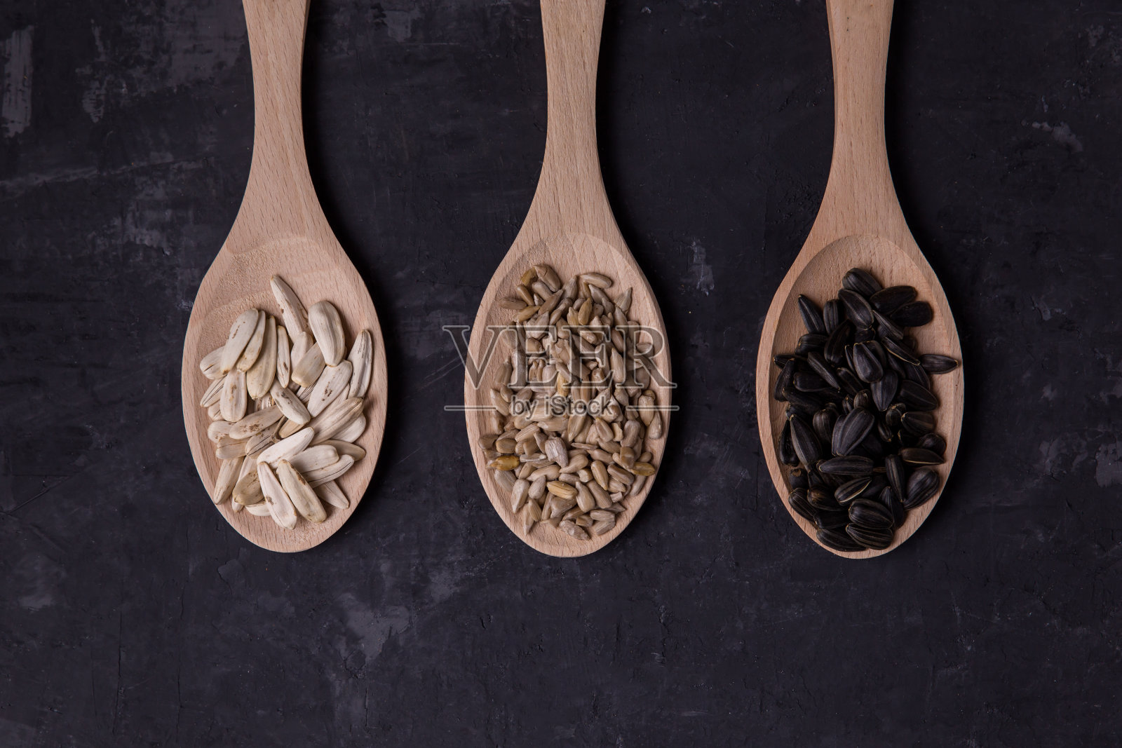 葵花籽是黑色的，白色的。土耳其的种子。没有剥去皮。勺子里的种子是不同的。模型俯视图深色背景照片摄影图片