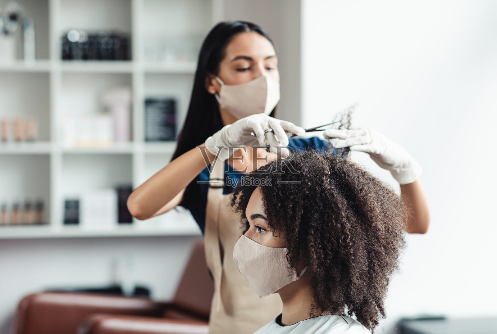 有Covid-19安全措施的理发师，为佩戴医用口罩的女性理发照片摄影图片