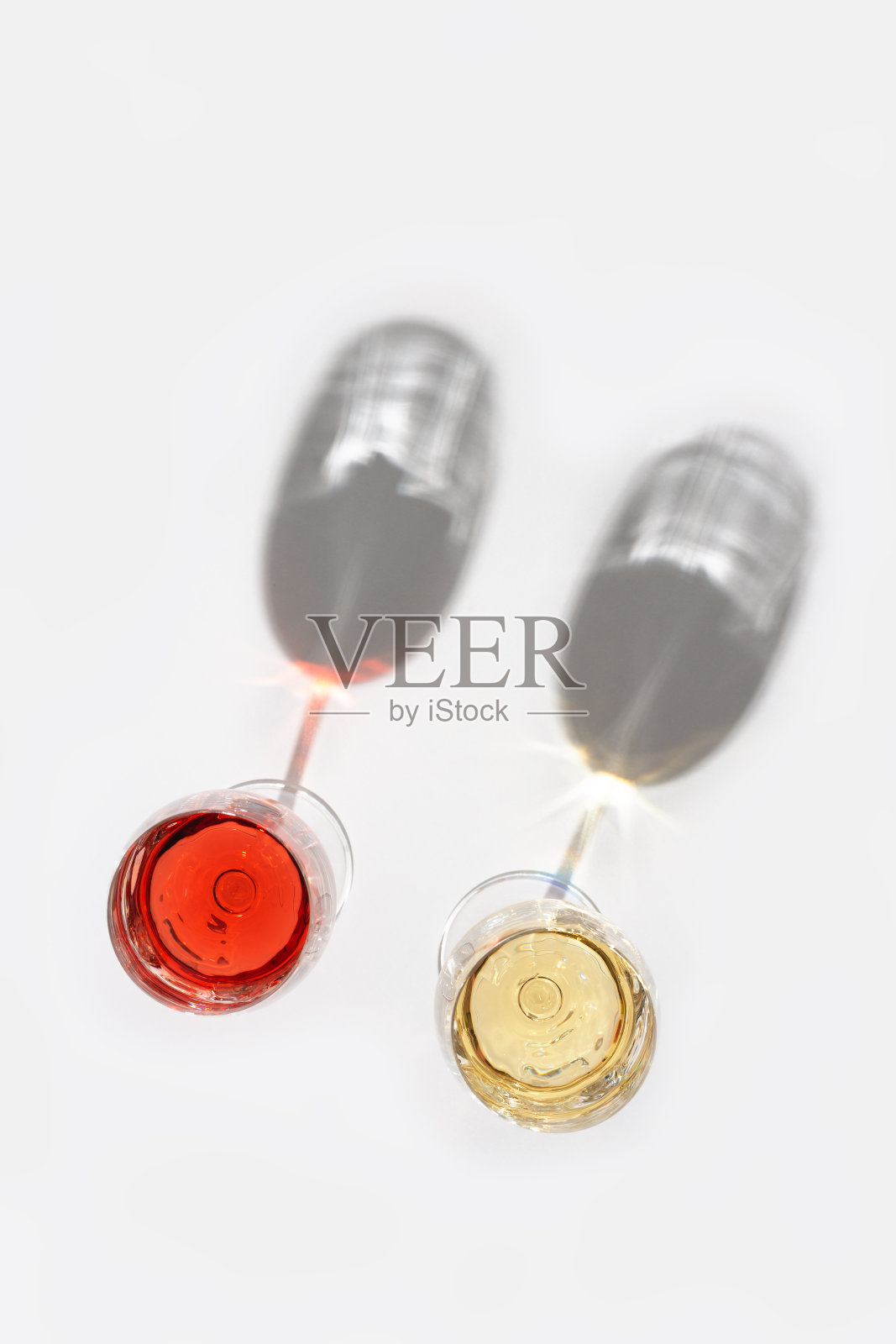 浅色背景下的玻璃杯中加入玫瑰和白葡萄酒。照片摄影图片