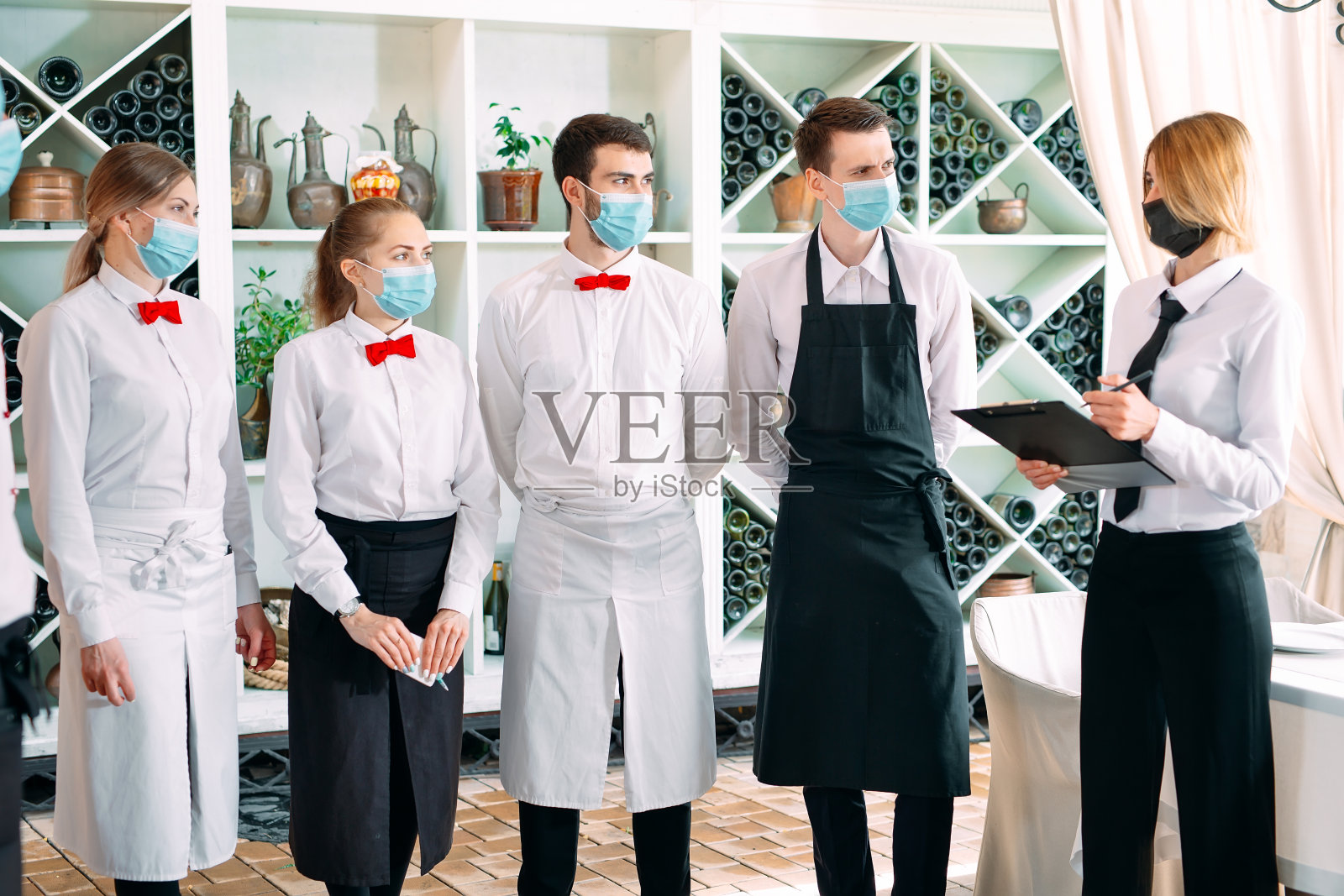 餐厅或酒店员工戴防护口罩。检疫结束。餐厅经理和他的员工在露台上。与餐厅主厨互动。照片摄影图片