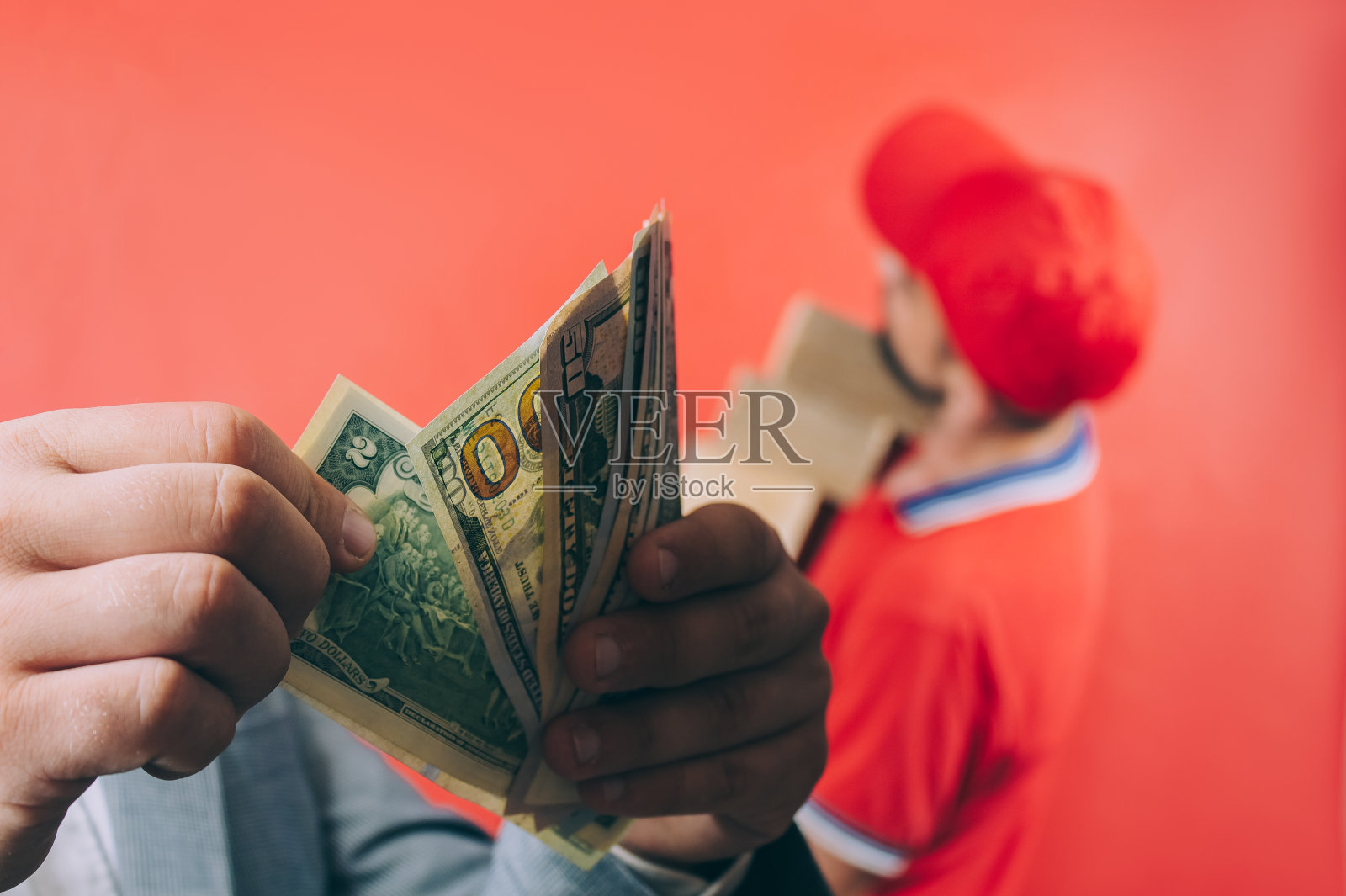 老板手里拿着美元付给雇员钱。红色背景上的概念。照片摄影图片