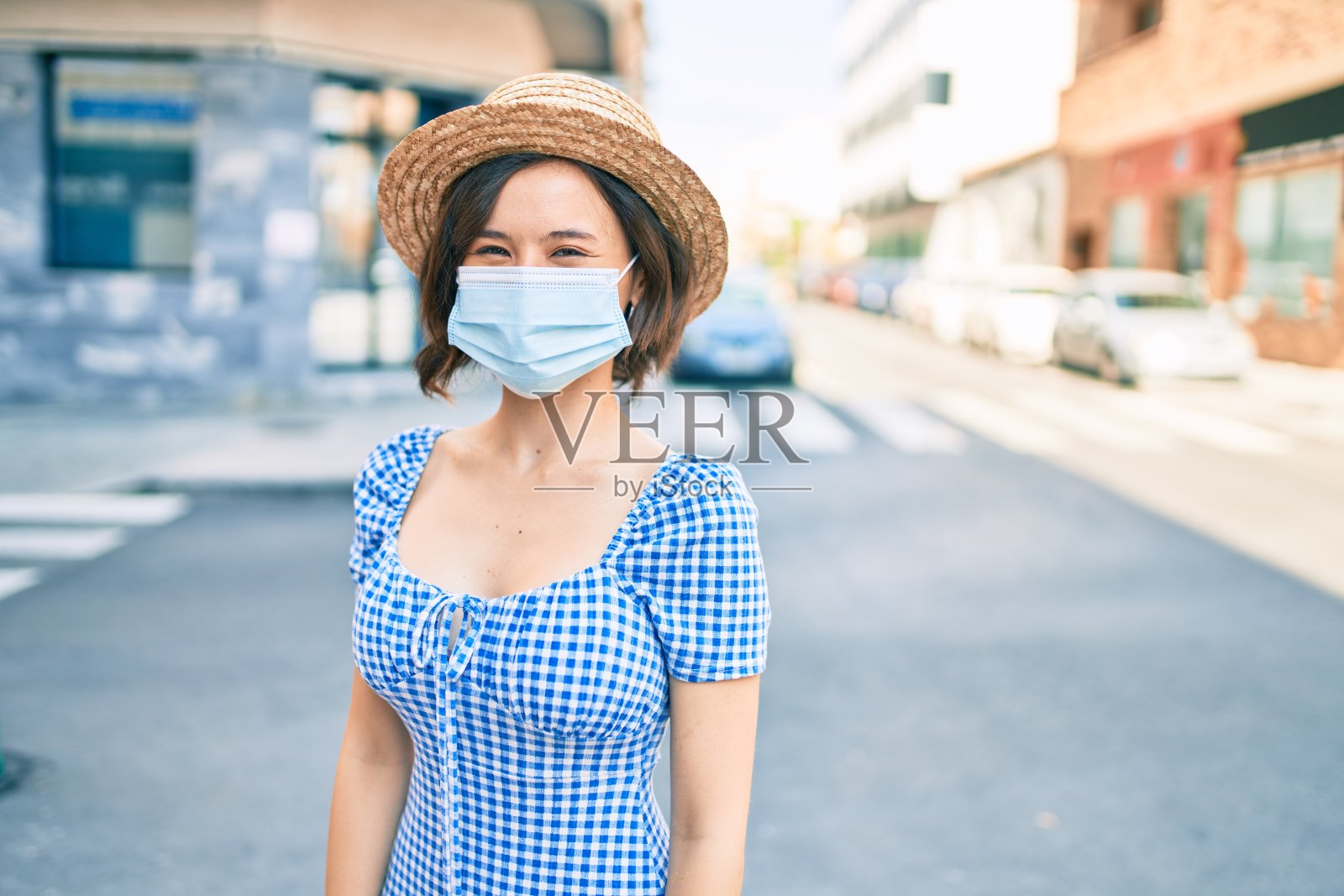 年轻美丽的女孩戴着医用口罩走在城市的街道上照片摄影图片