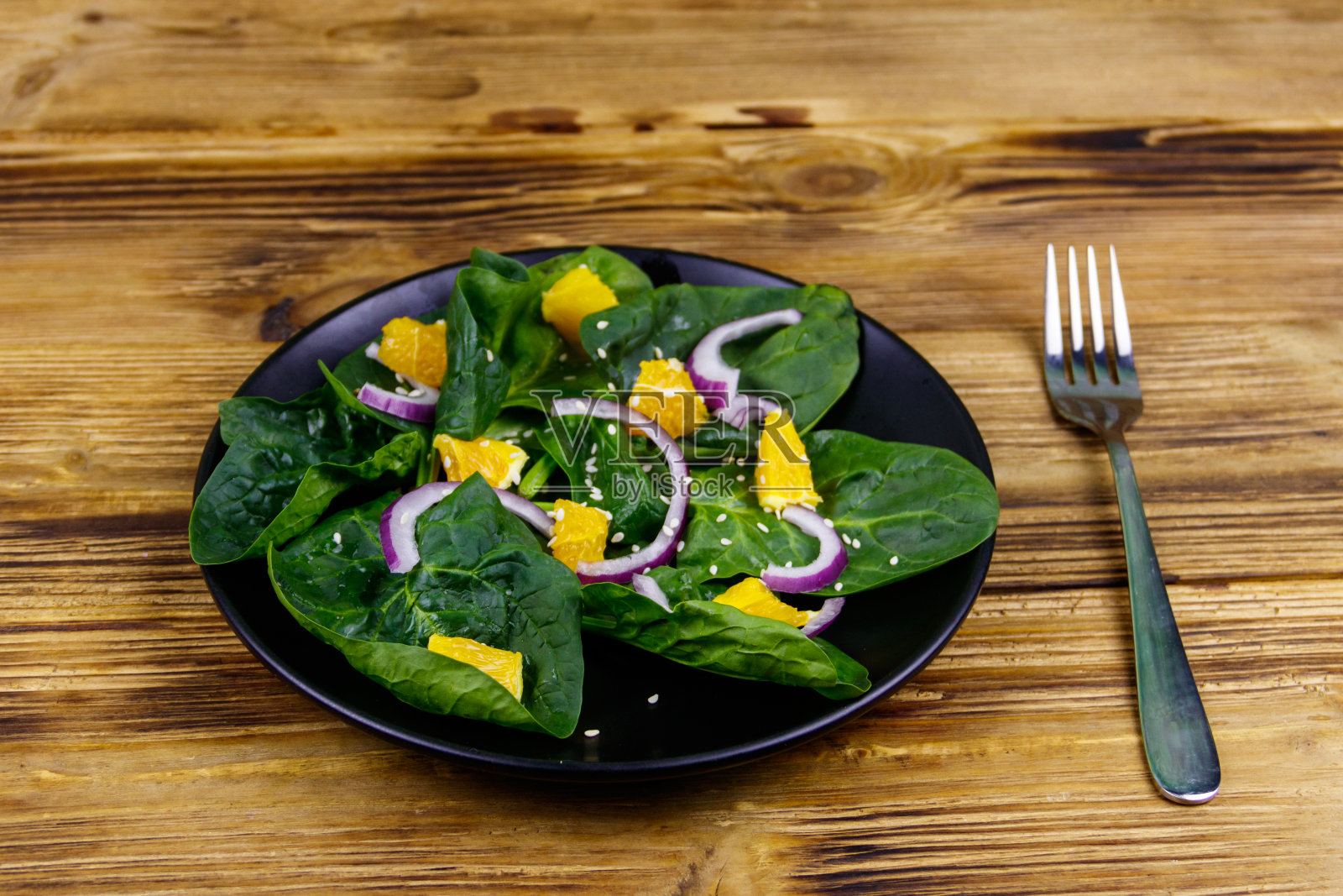 美味的沙拉，有菠菜，橘子，红洋葱和芝麻种子在木桌上。健康食品或素食的概念照片摄影图片