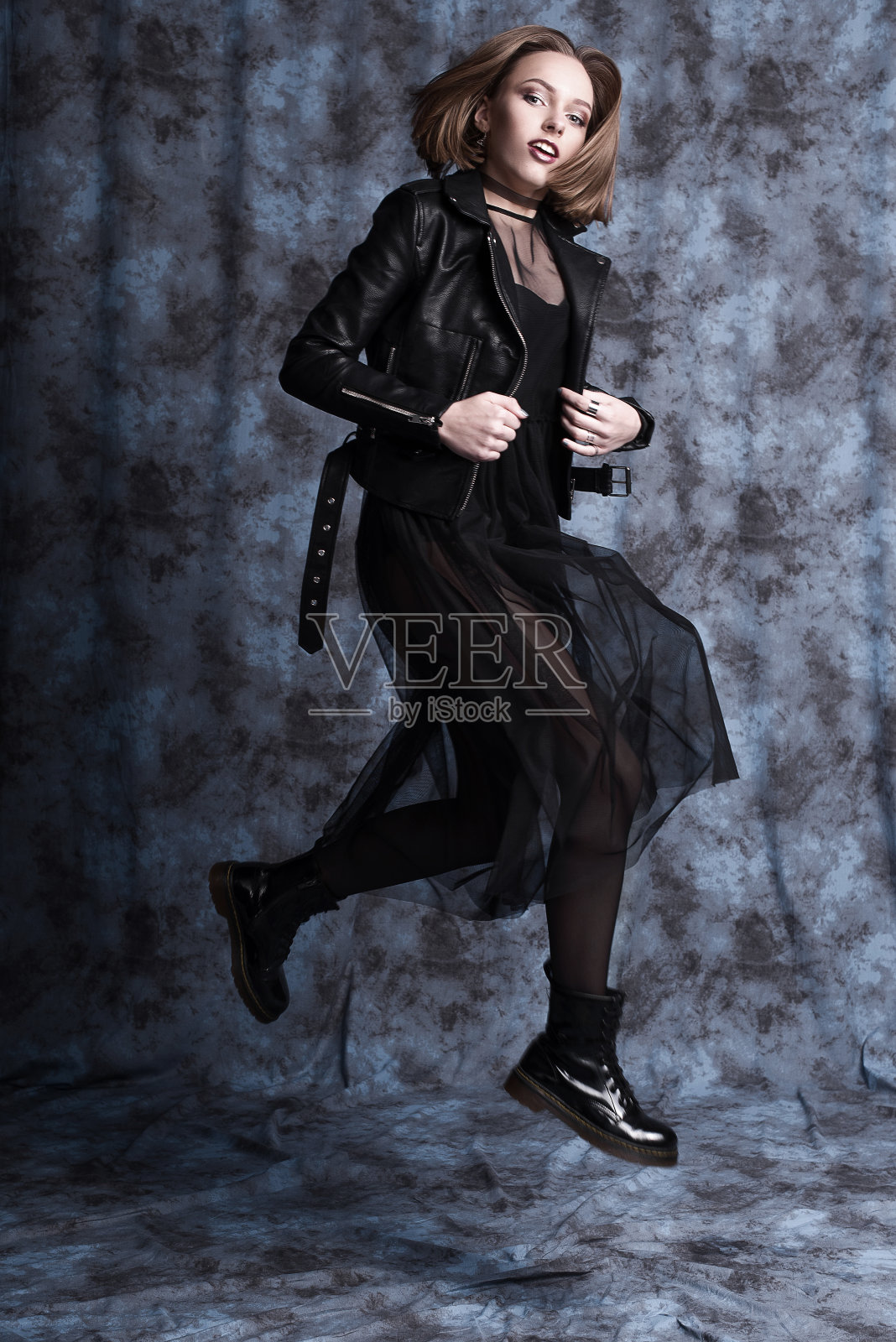 高端时尚看，魅力时尚漂亮的年轻女子模特与红色的嘴唇在潮人摇滚黑布在靴子跳。过拍摄照片摄影图片