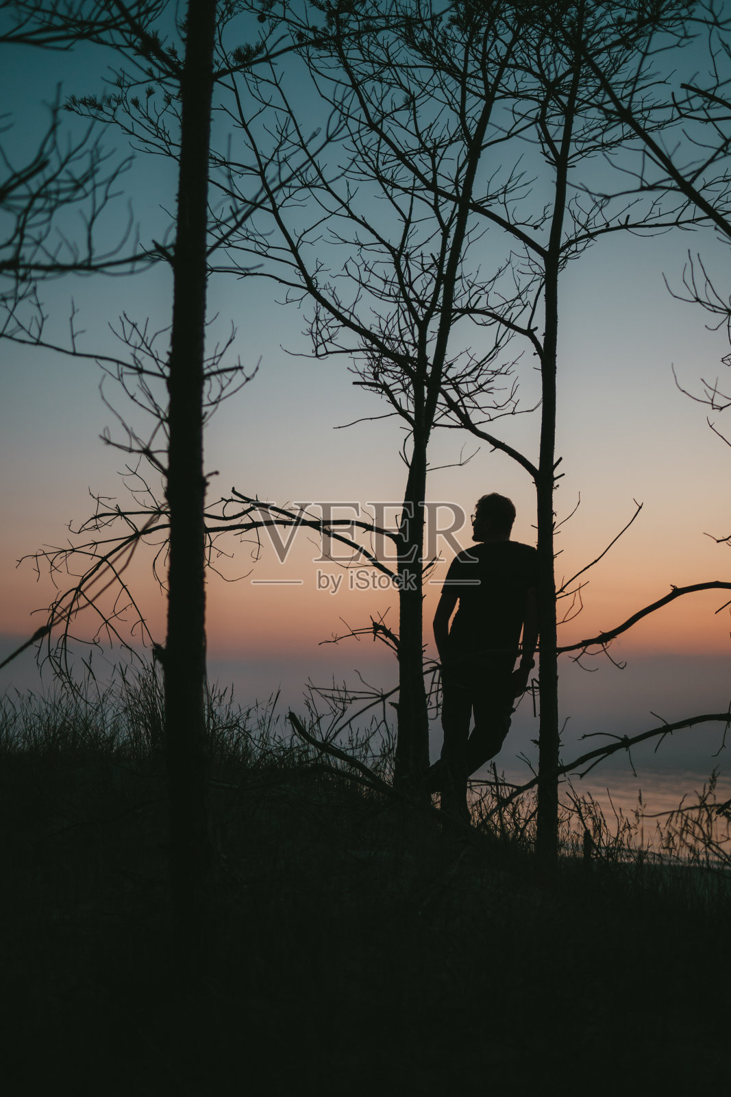 海上日落。人类探索着荒野，悬崖峭壁的海岸线照片摄影图片