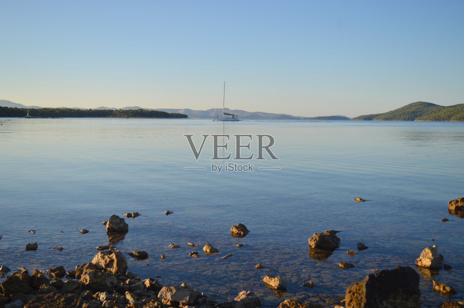 清晨，风平浪静的海面上航行着一艘帆船。Jadrija, Sibenik照片摄影图片