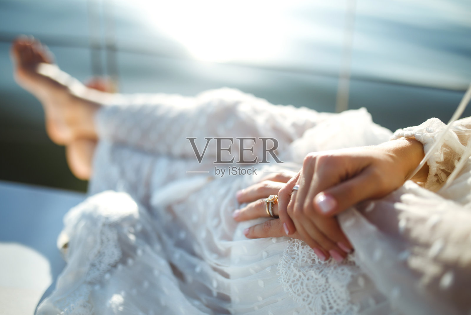 美丽时尚的新娘在海上的游艇上，穿着奢华的白色蕾丝礼服，捧着婚礼花束。照片摄影图片