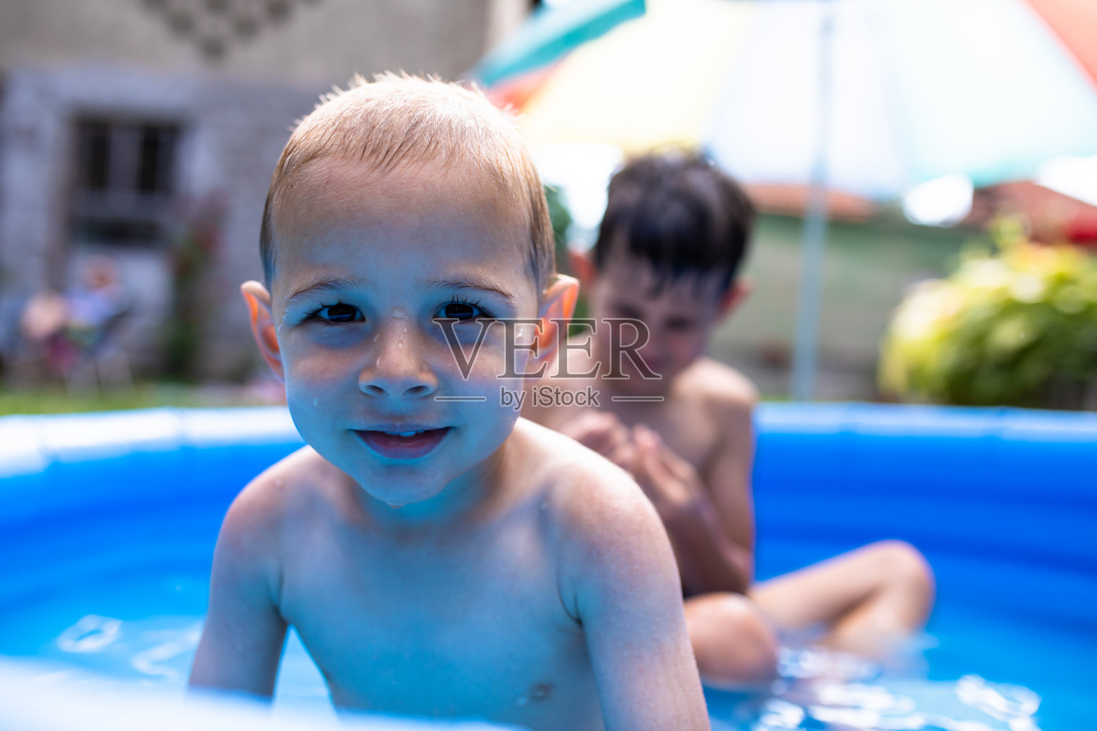 两个可爱的男孩坐在嬉水池里照片摄影图片