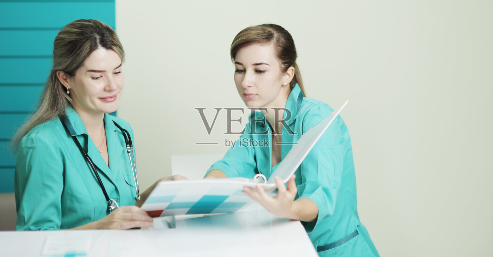 两位女医生或护士在讨论病人的治疗。在脖子上放听诊器照片摄影图片