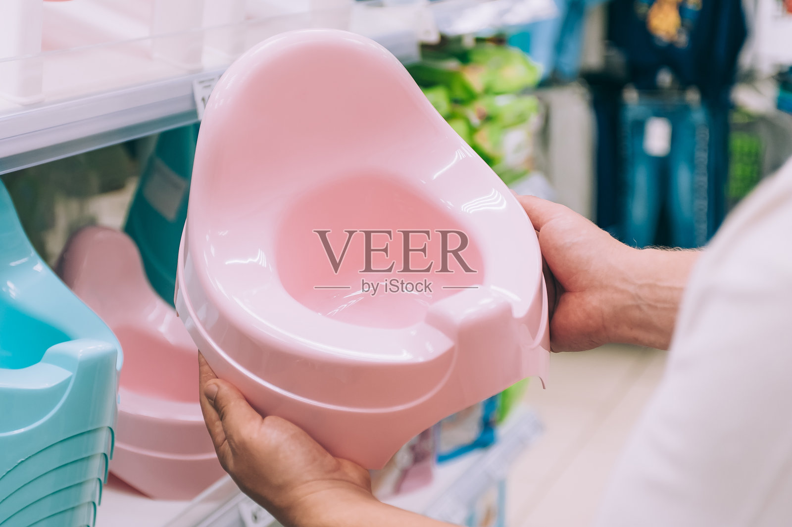 一个男人在商店里给婴儿选了个便盆。照片摄影图片