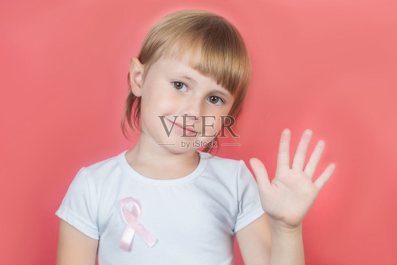 小女孩穿着白色t恤和粉红色的乳腺癌意识丝带，手拿停止标志照片摄影图片