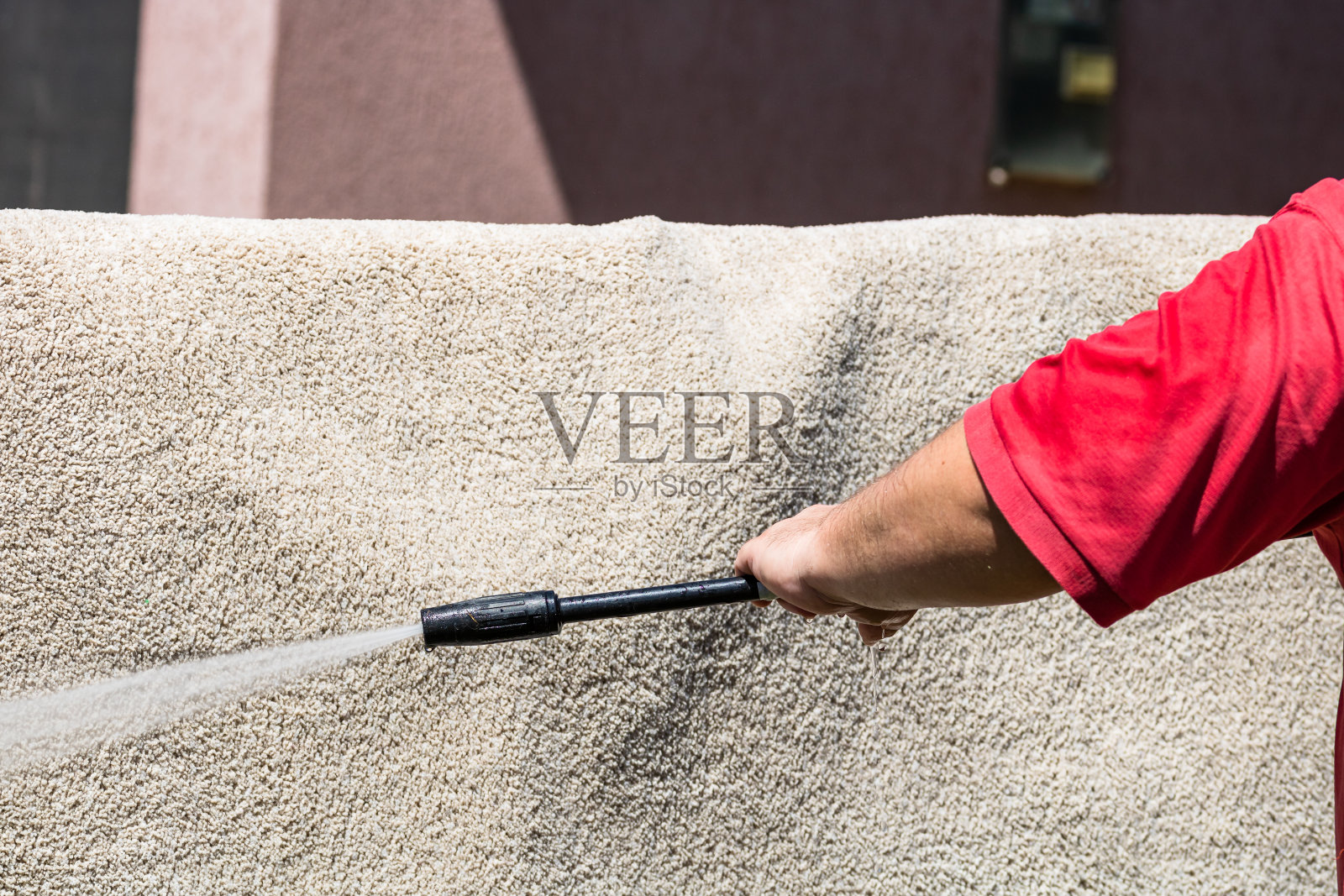 用高压洗衣机清洗地毯的特写。用高压水洗枪清洗地毯。打扫屋子的概念。照片摄影图片