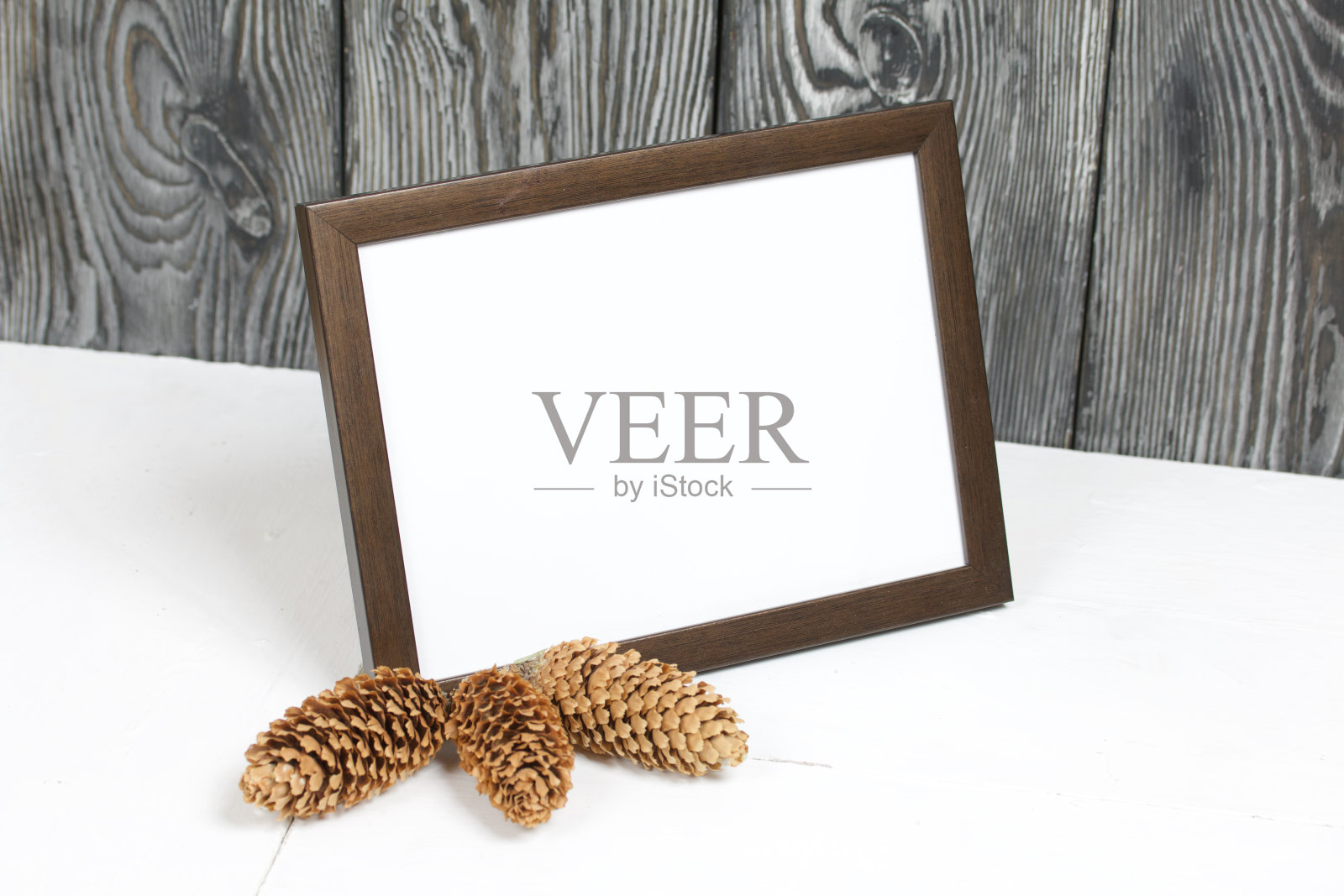 木制的相框，白色的领域为题字或图片。附近是冷杉球果。照片摄影图片