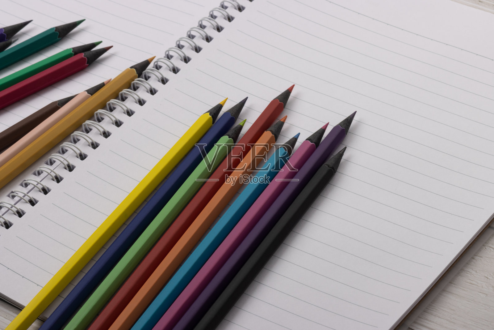 多色黑木铅笔摆放在一个螺旋笔记本上。本空间照片摄影图片