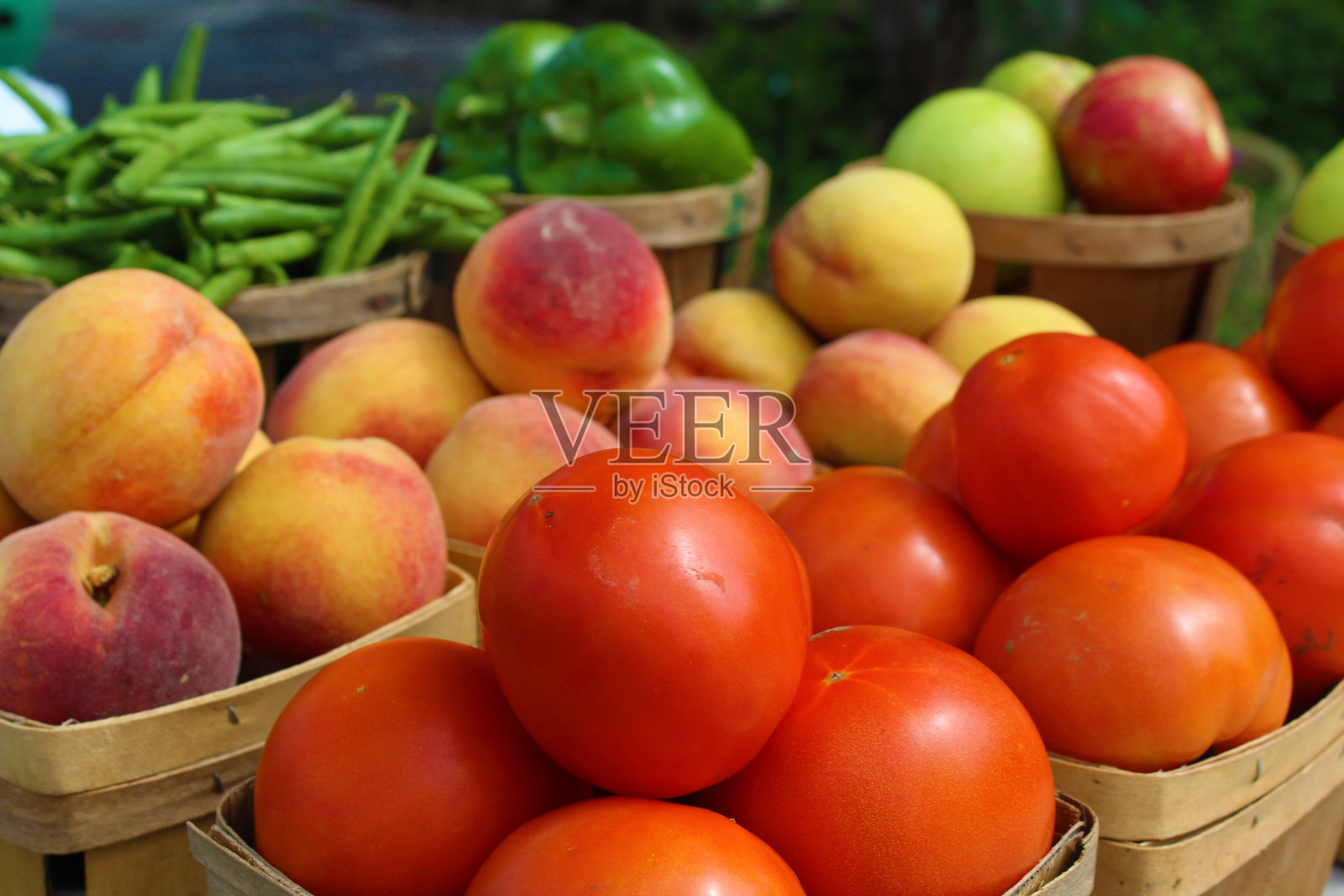 在农贸市场里，桃子、西红柿、菜豆和苹果都装在篮子里照片摄影图片