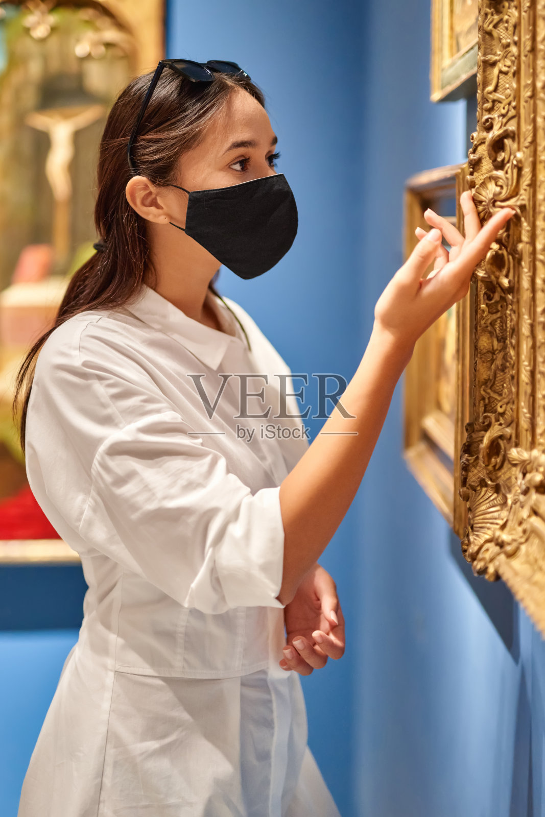 戴着防毒面具的女游客在历史博物馆里看照片。照片摄影图片