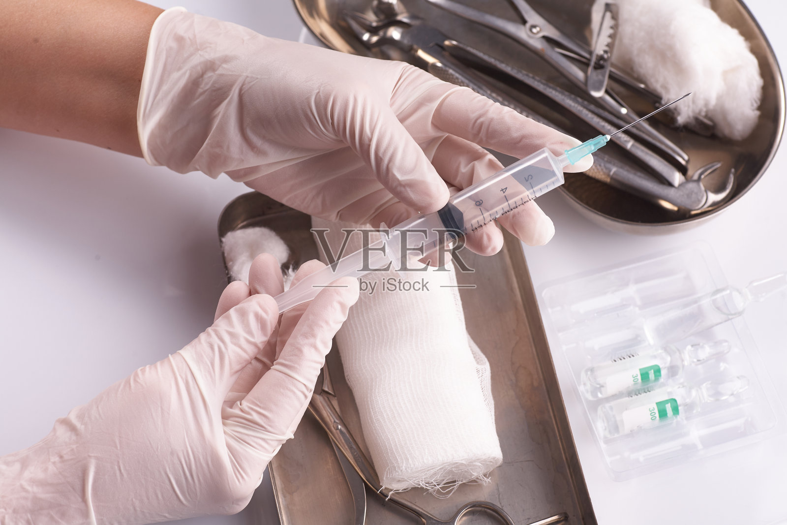 医用台背景上医生手中的医用注射器。医生的手在医疗手套。照片摄影图片