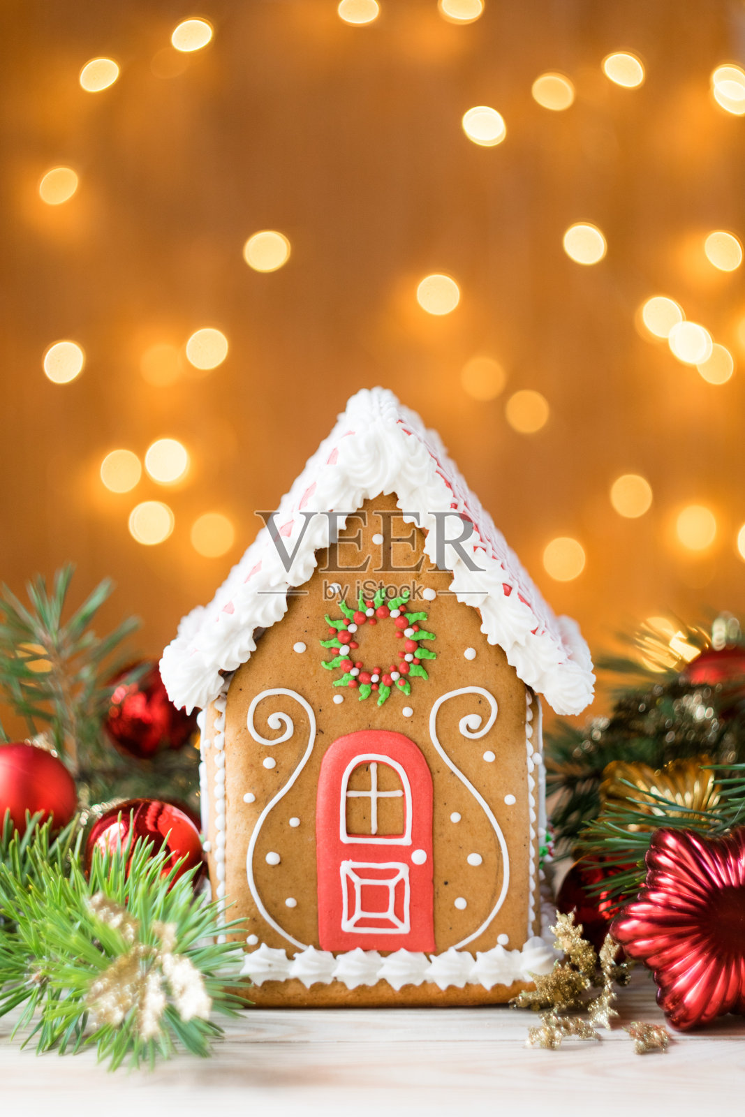 漂亮的姜饼屋与松树枝和圣诞装饰，灯光在背景，垂直方向，选择性焦点照片摄影图片