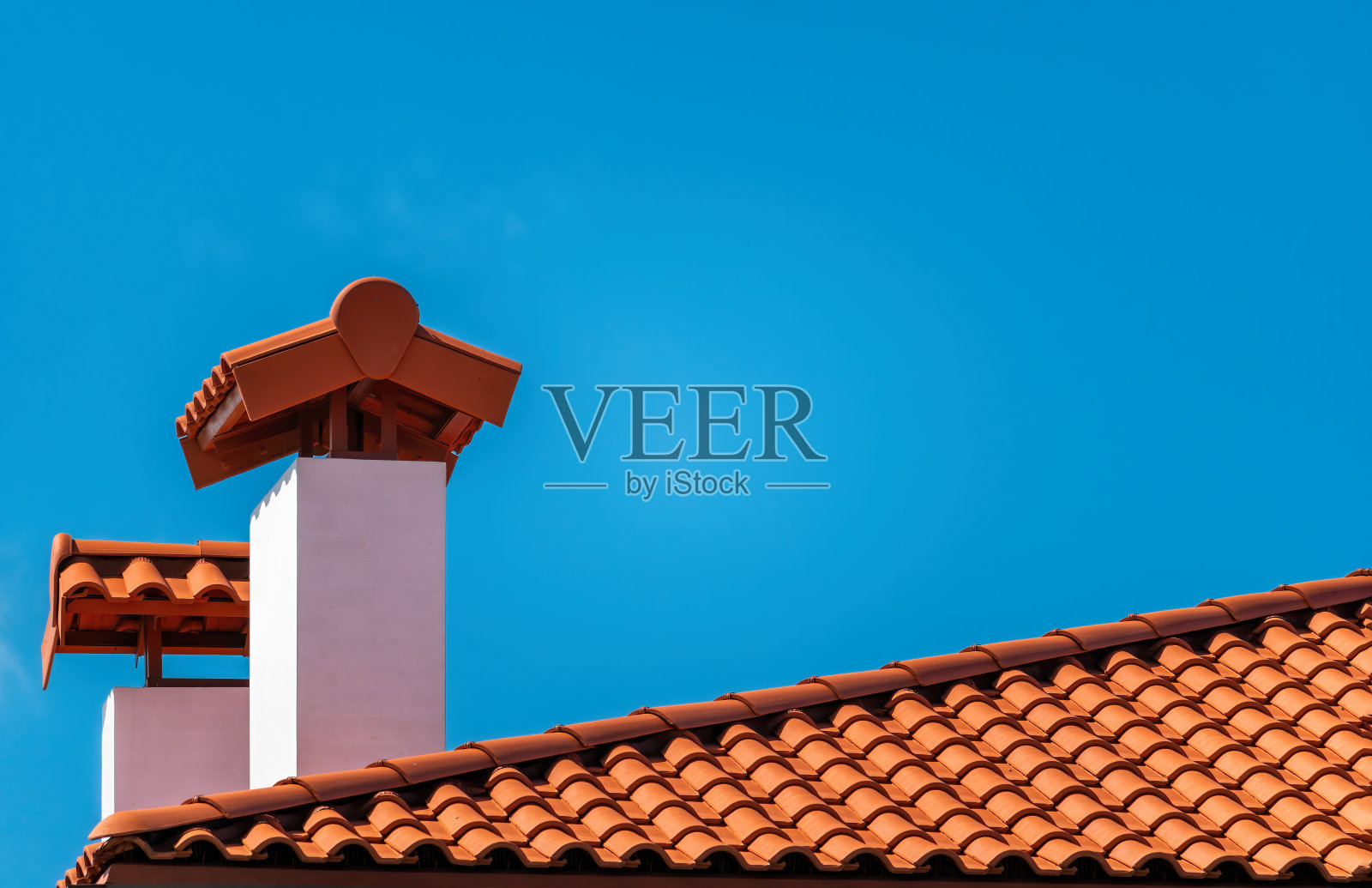 蓝天下的棕色瓦屋顶。这张照片分成两部分。一部分是黏土瓦做的屋顶，另一部分是蓝天。瓦屋顶表面为棕色，色泽、纹理、图案自然照片摄影图片