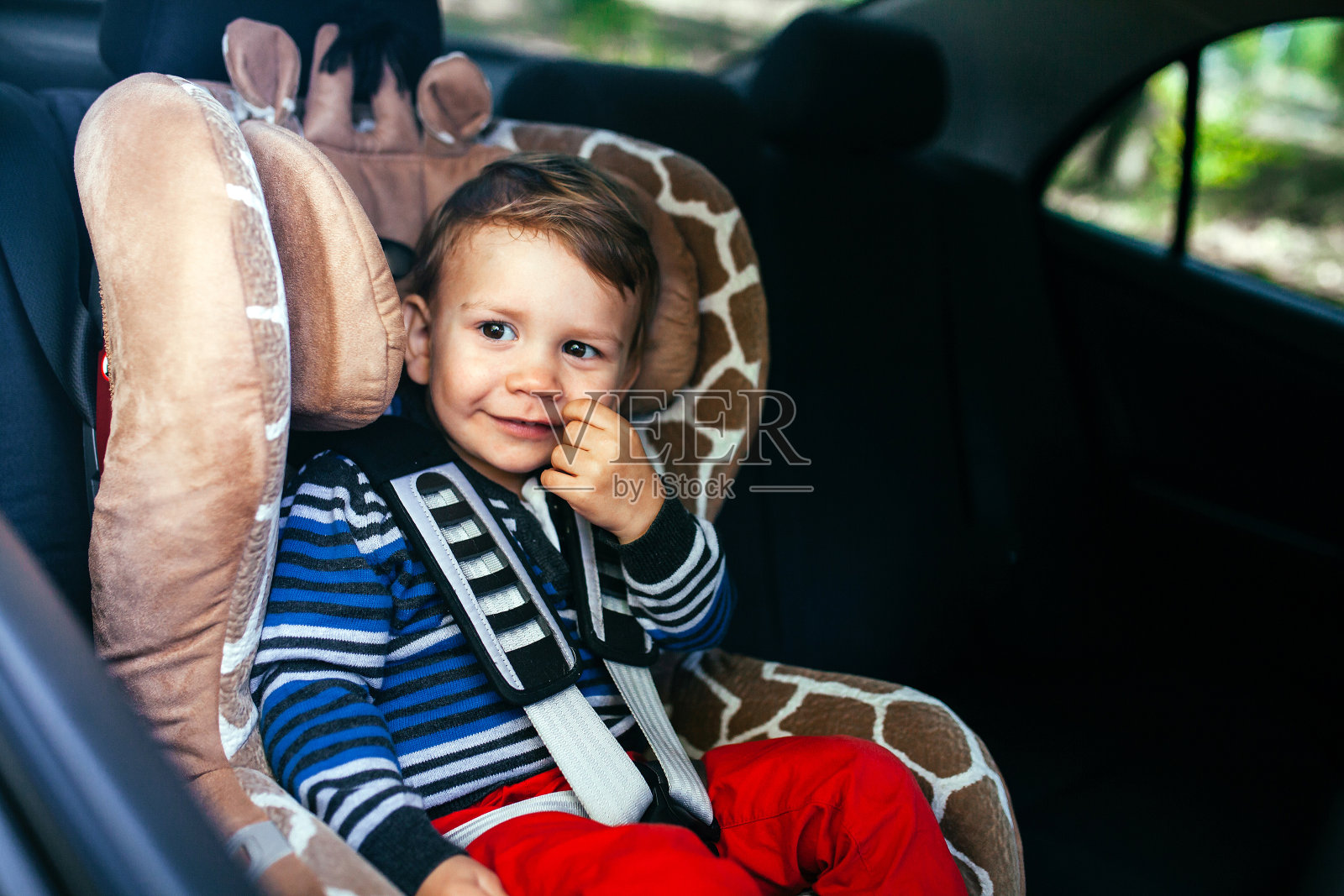 可爱的小男孩坐在安全座椅上。照片摄影图片