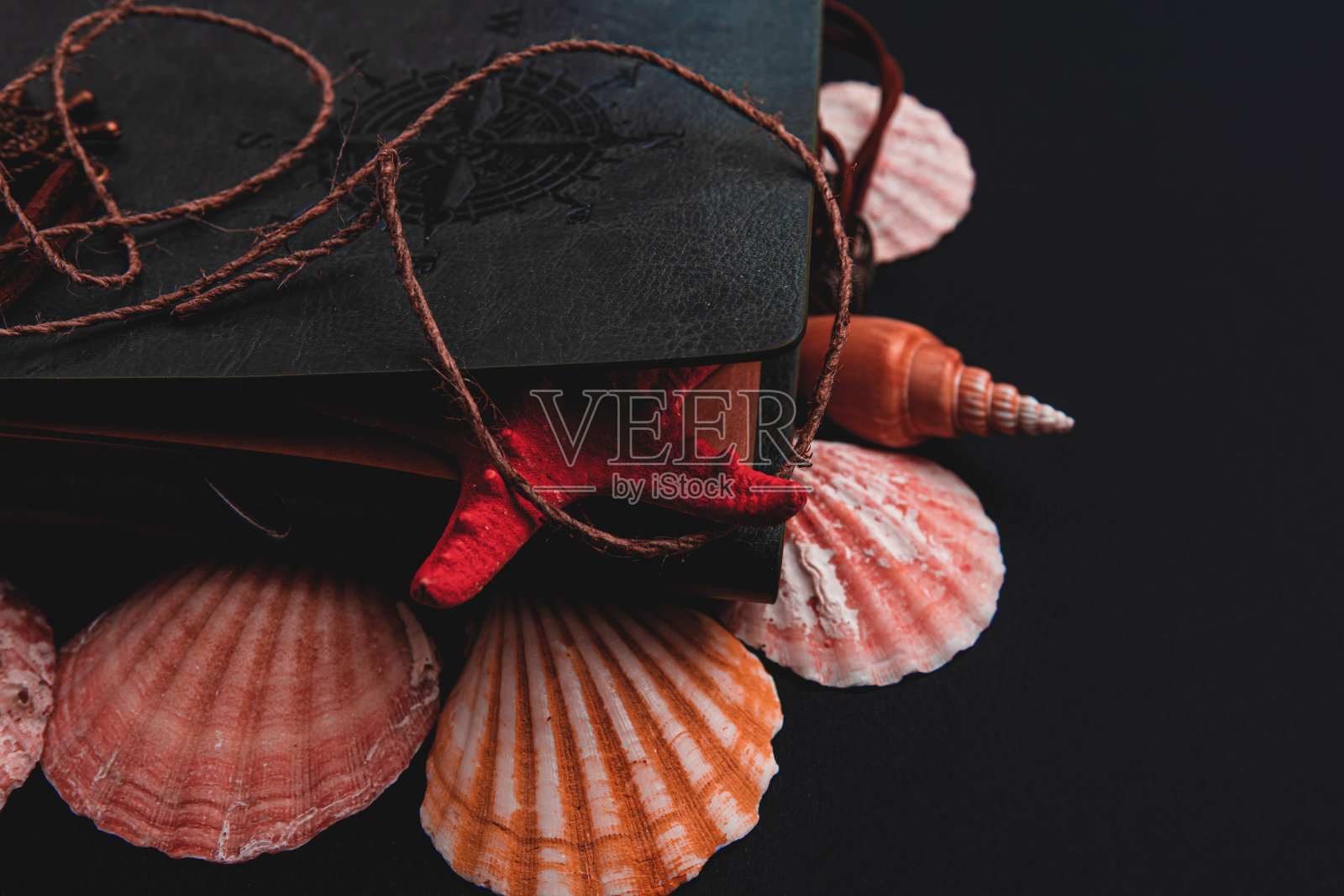 灰色皮面日记本与海星，贝壳，指南针，舵轮，鞭笞在一个黑色的背景照片摄影图片