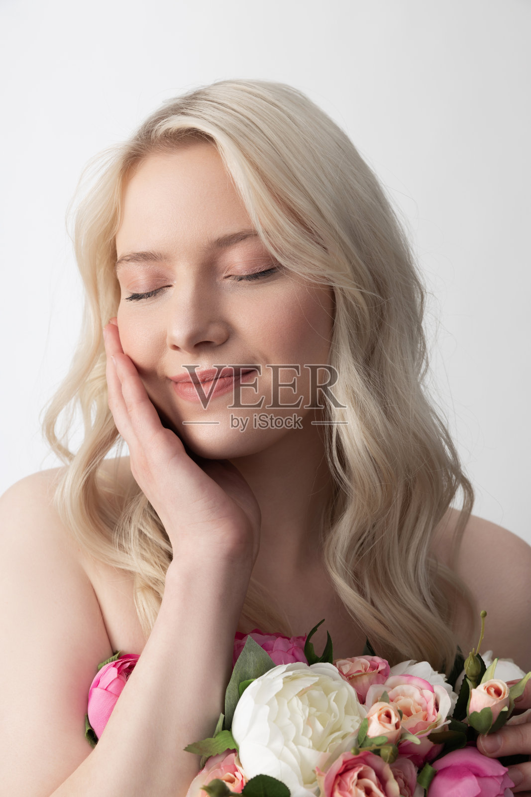 美丽的年轻女子与鲜花触摸脸和微笑照片摄影图片