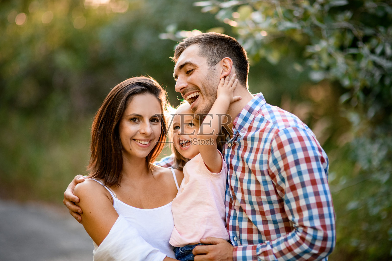 快乐的爸爸妈妈和可爱的小女儿的全家福照片摄影图片