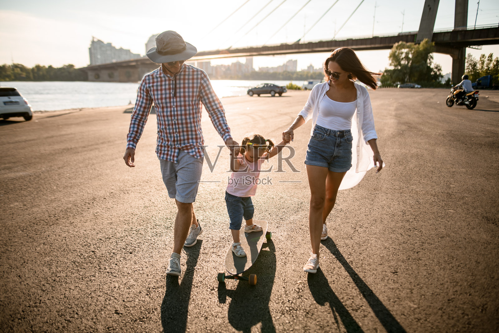 在阳光明媚的夏日，一对家庭夫妇牵着孩子的手散步照片摄影图片