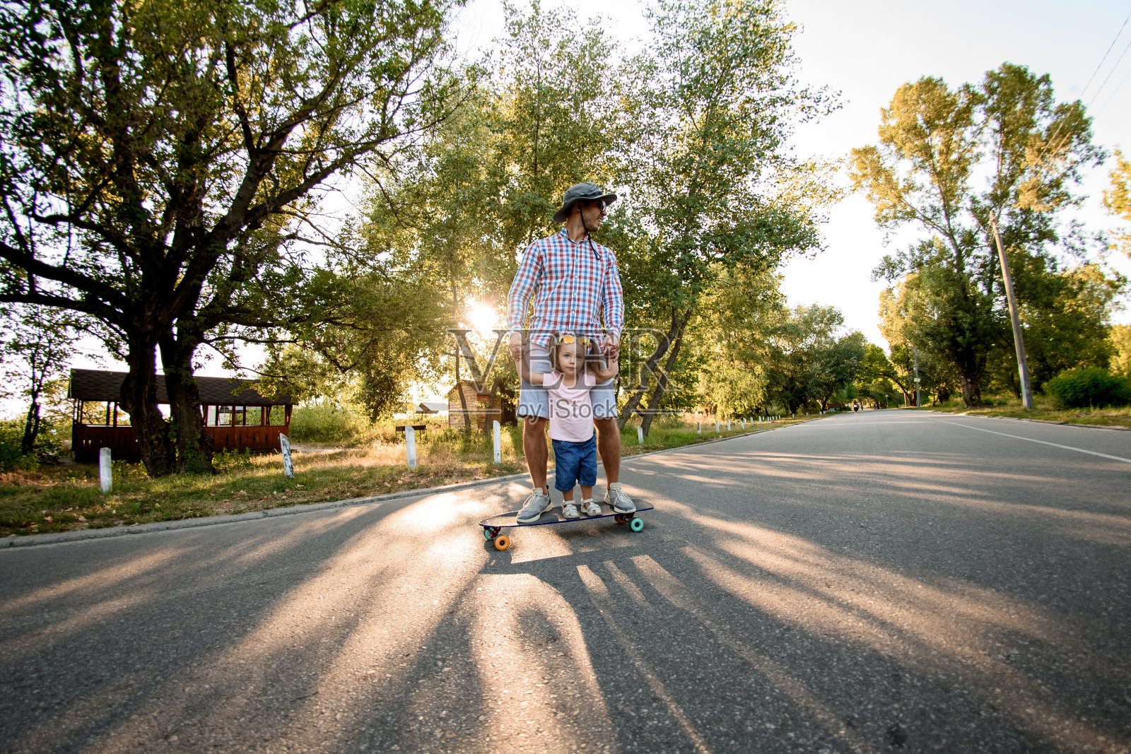 一个成年人和他的小女儿在公园的路上玩滑板照片摄影图片