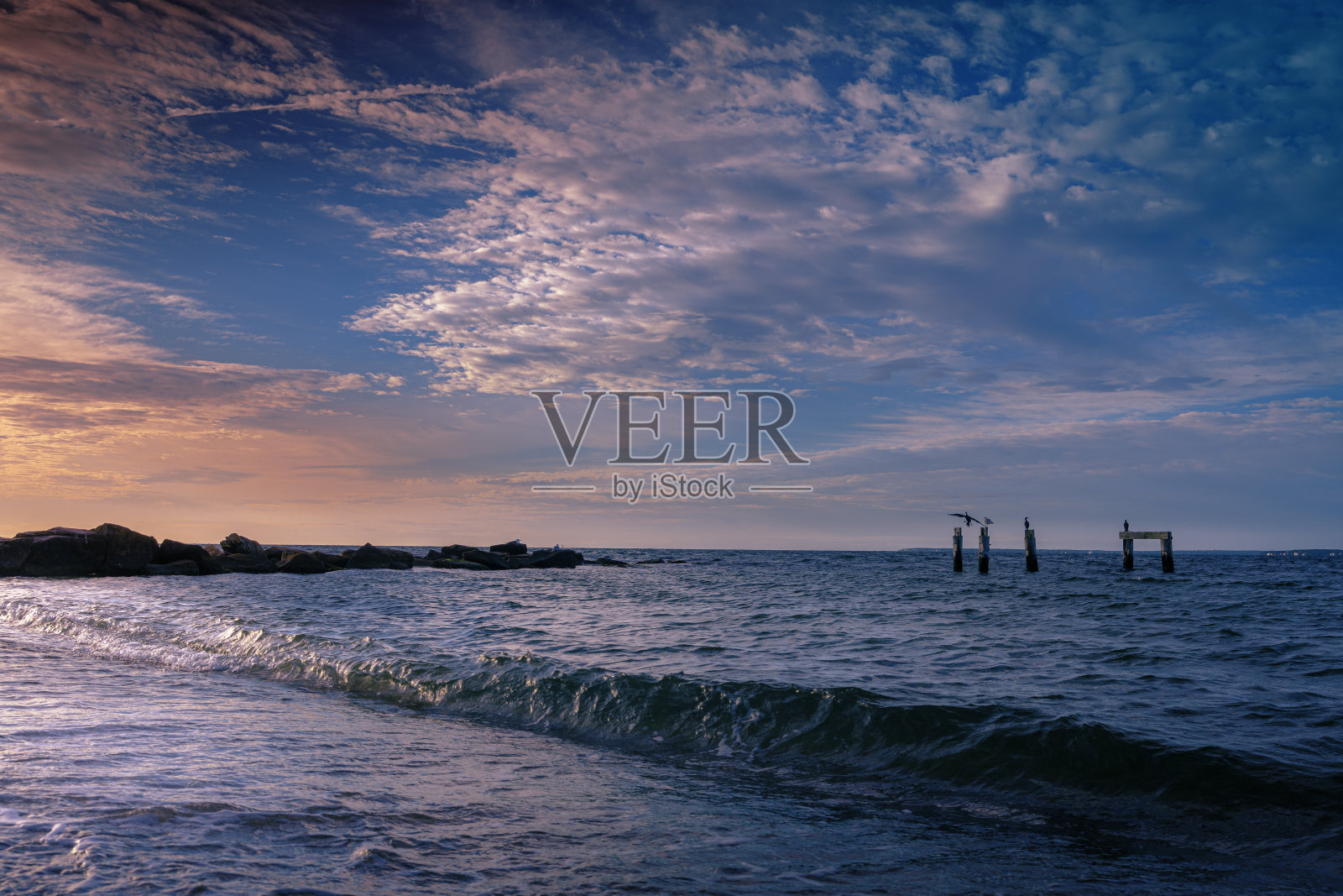 宁静的粉红色日出海景和积云在码头和毁坏的码头上照片摄影图片