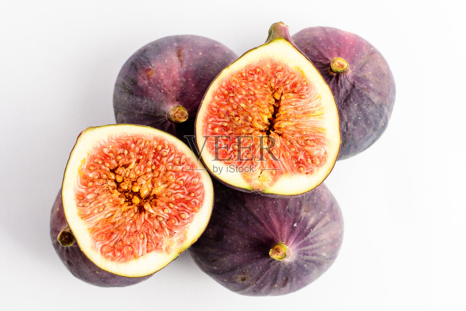 白色的桌子上放着新鲜成熟的有机无花果，两个完整的无花果，还有一个被切成两半，柔焦特写，俯视图照片摄影图片