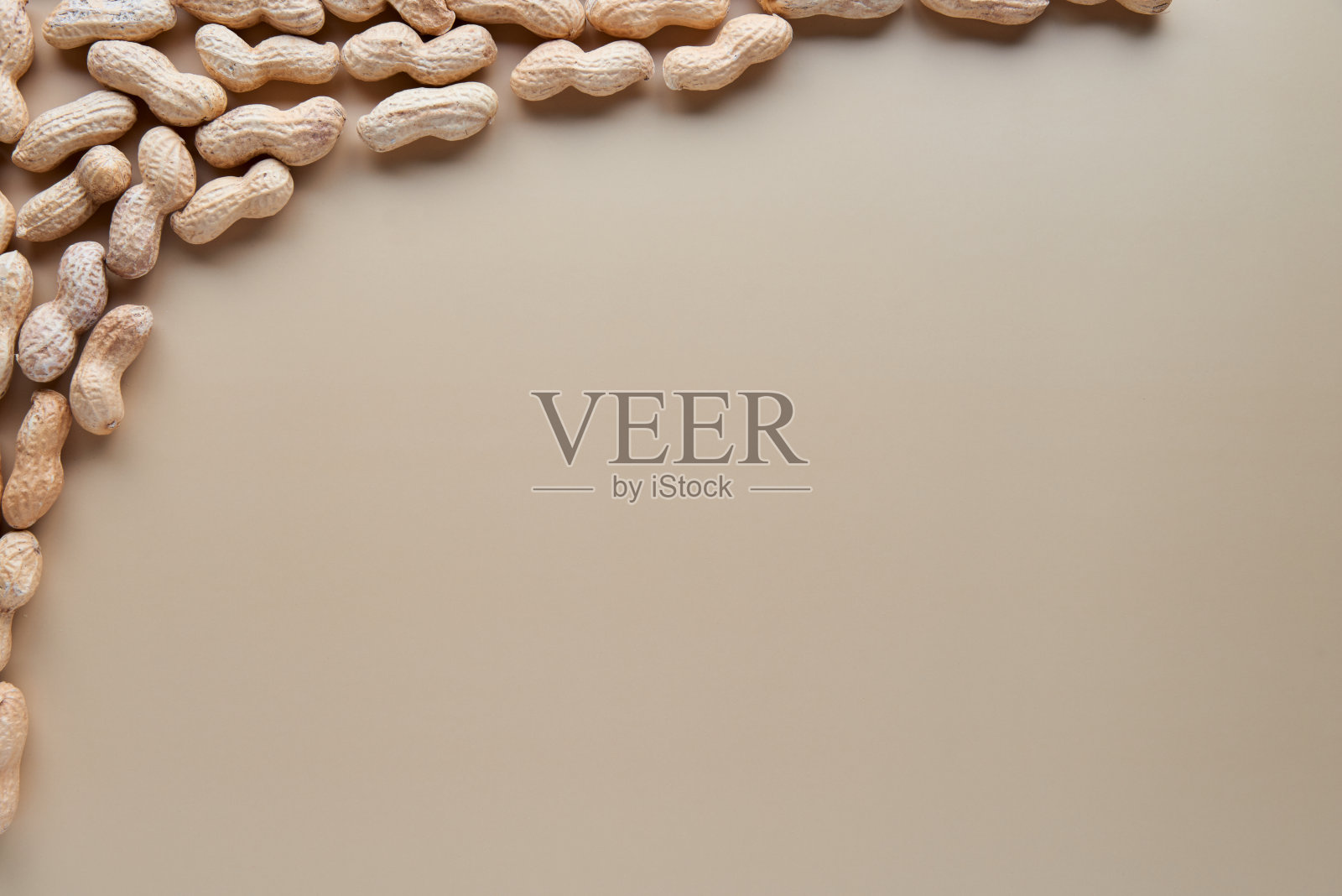 烤unsaltedÂ未剥皮花生壳分离在米色背景。食品、配料、有机素食蛋白、健康饮食营养理念。顶部视图与复制空间。照片摄影图片