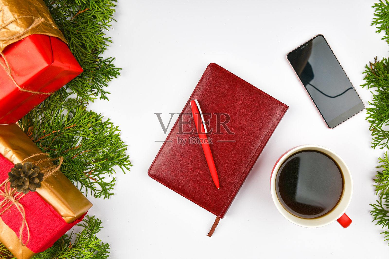 圣诞背景来自记事本，电话，咖啡杯。陶瓷红杯加黑咖啡。新年的布局。从以上观点。一个女人的手在静脉笔记本上写字照片摄影图片