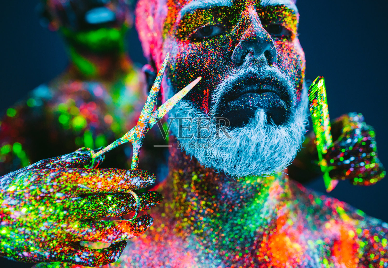 的概念。理发店里的大胡子男人。一个留着时髦胡子的男人正在理发店里理发。这个人用紫外线粉做装饰照片摄影图片