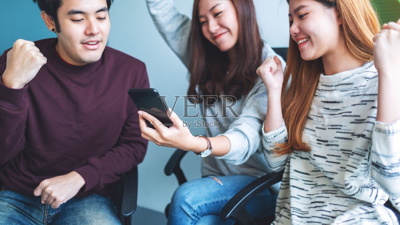 一群年轻人玩得很开心，一边看手机一边庆祝照片摄影图片