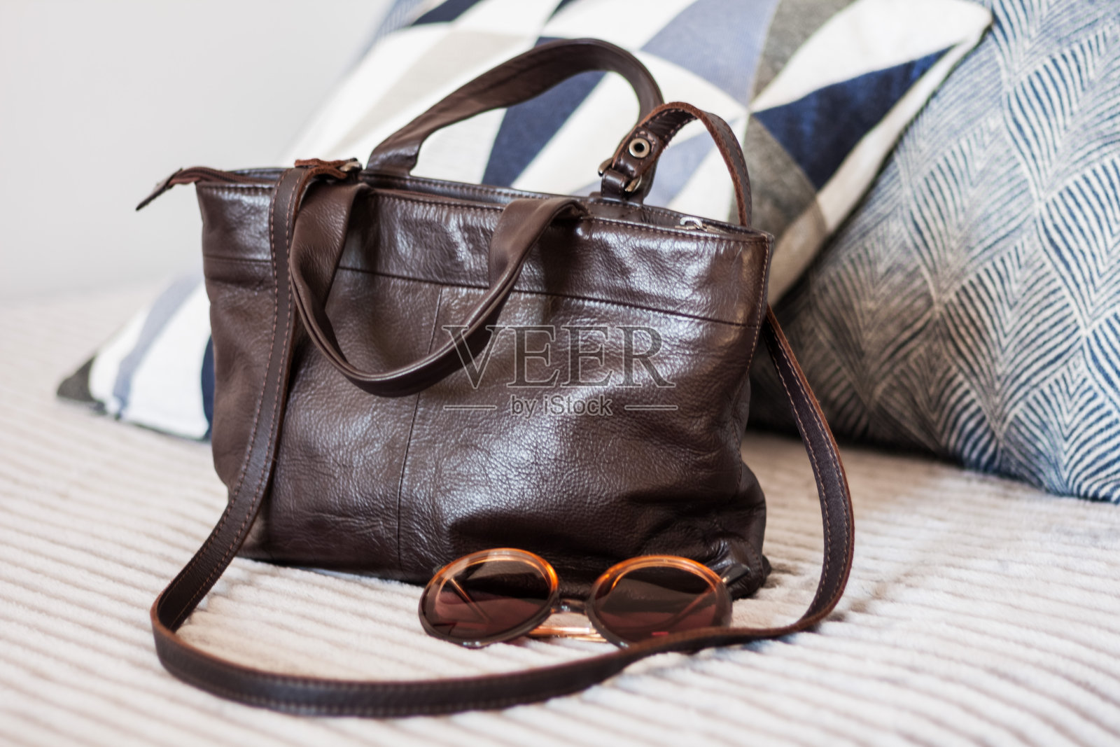 灰色沙发上的棕色皮包，女性配饰照片摄影图片