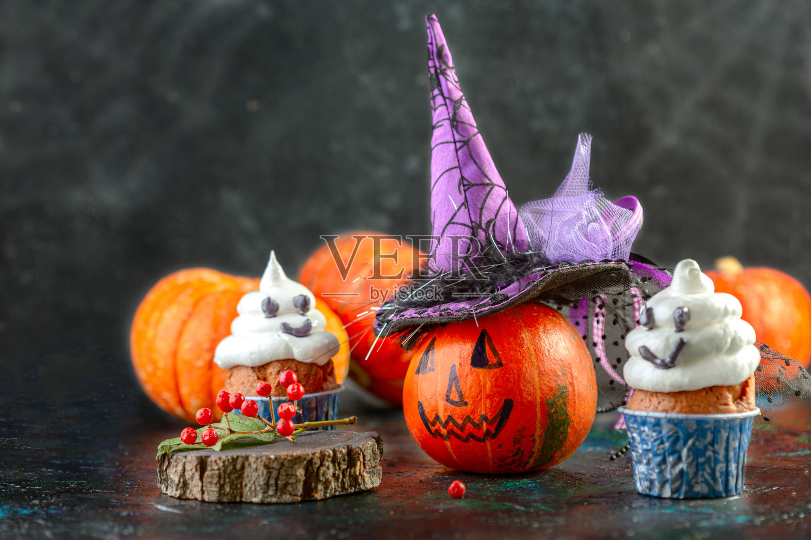 万圣节的幽灵纸杯蛋糕和戴女巫帽的南瓜。照片摄影图片
