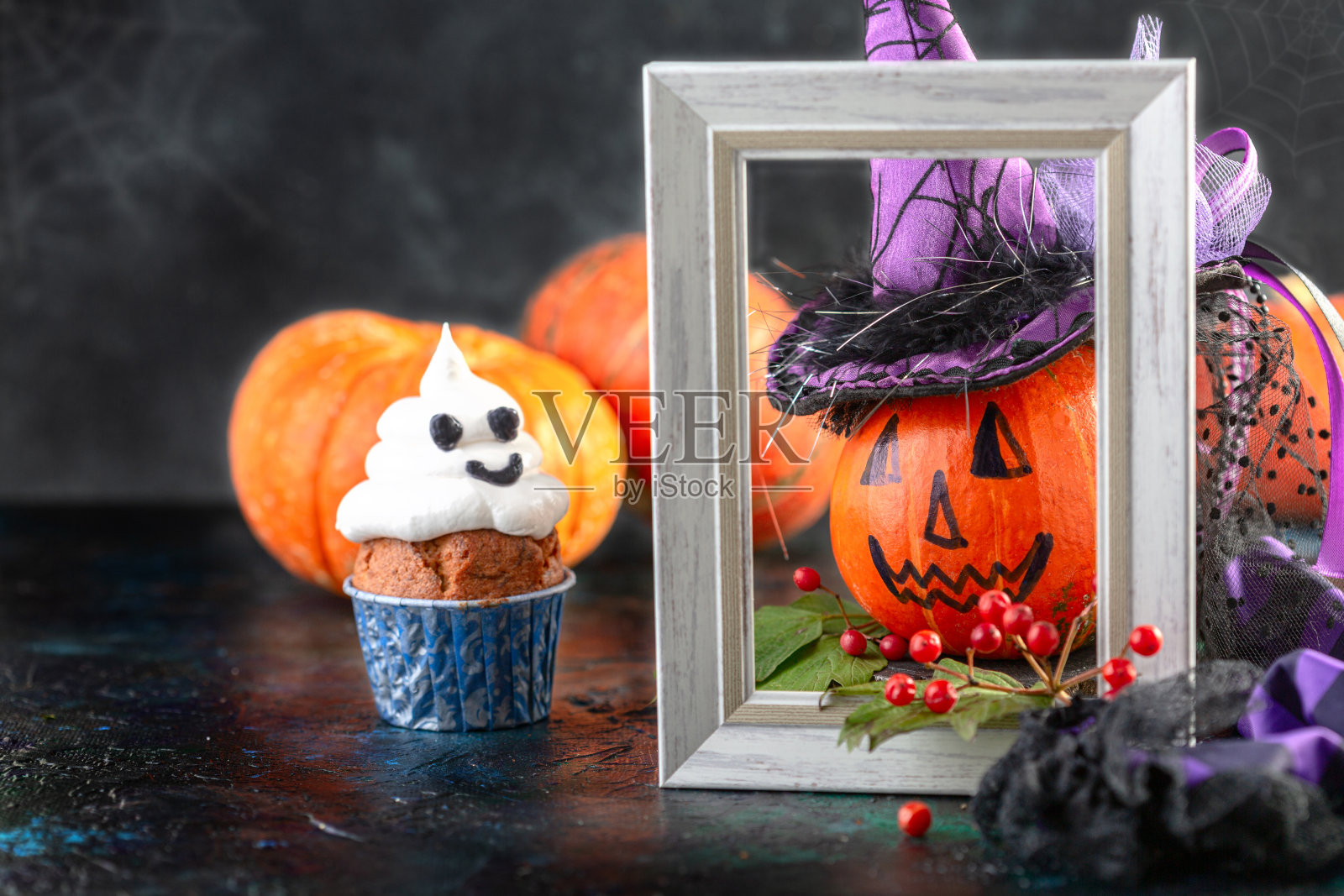 戴女巫帽的南瓜和万圣节幽灵纸杯蛋糕。照片摄影图片