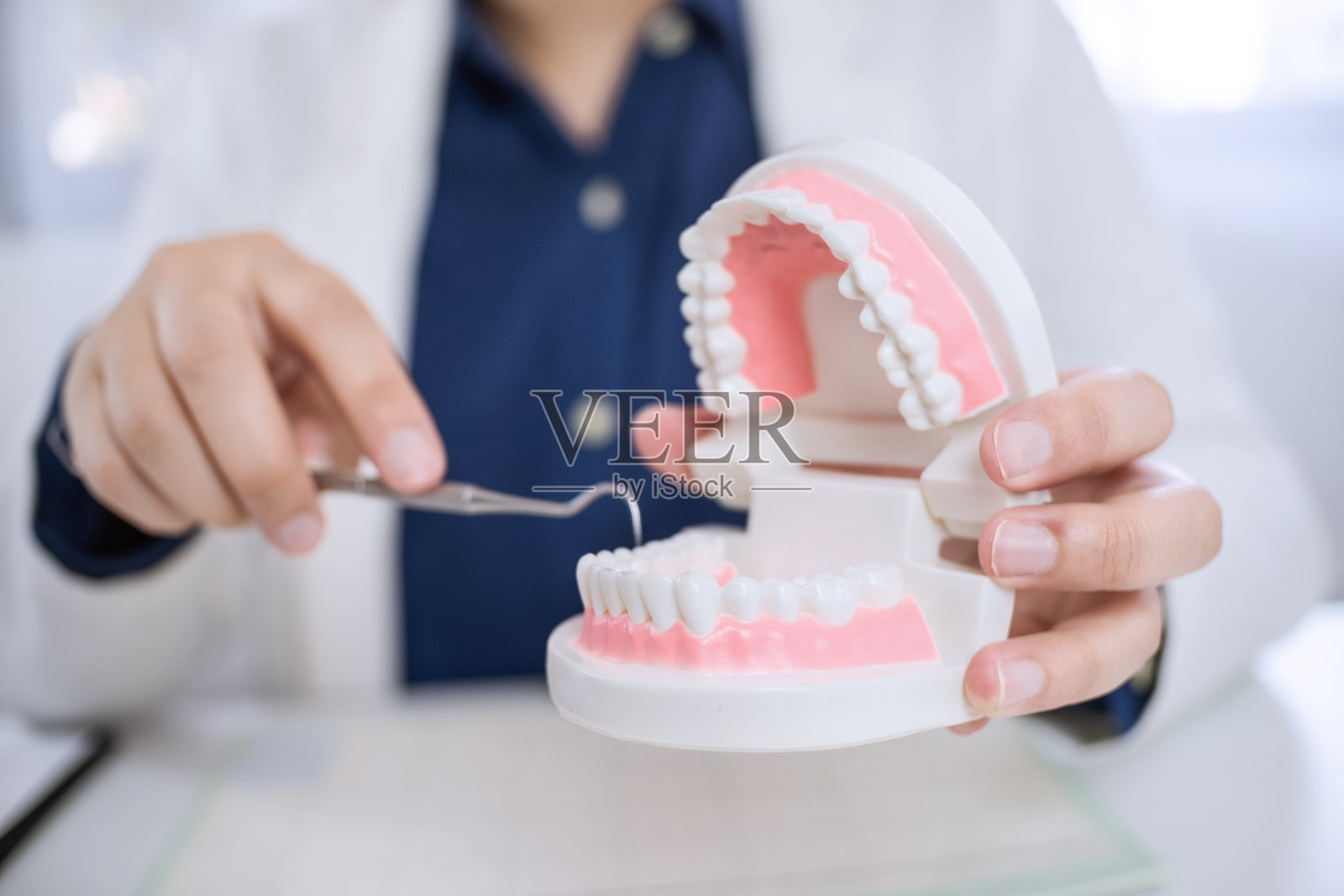 牙科医生在诊所用牙科模型向病人解释。照片摄影图片