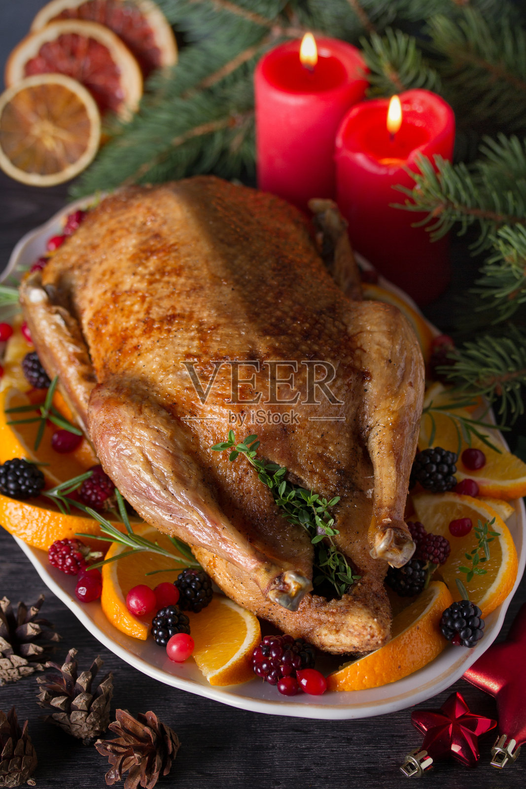 整只烤鸭配橙子，浆果和香草照片摄影图片