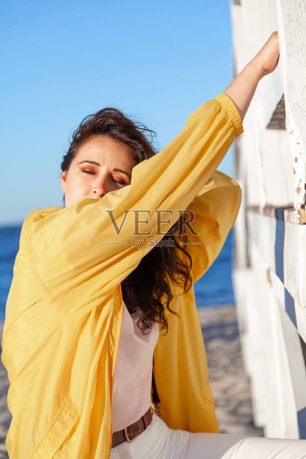 沙滩上的大女孩靠在木结构上照片摄影图片