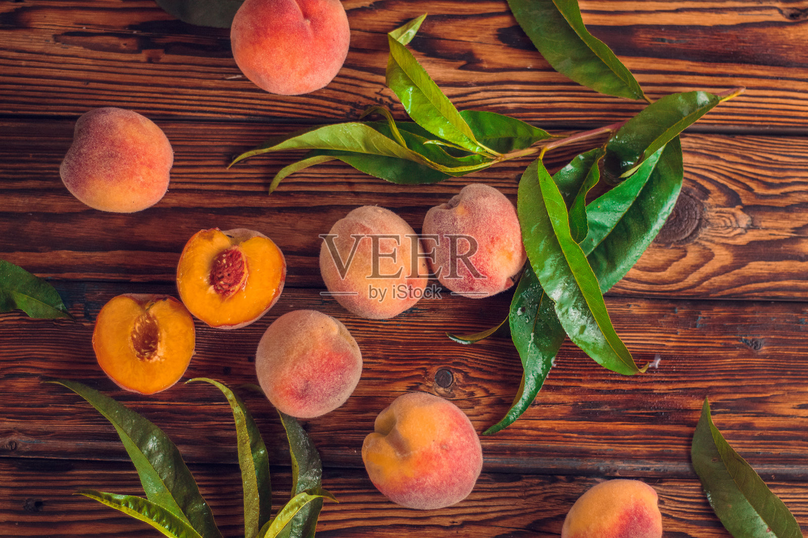 橙色的桃子和绿色的叶子在木制的背景。切片水果，复制空间，俯视图平铺。照片摄影图片